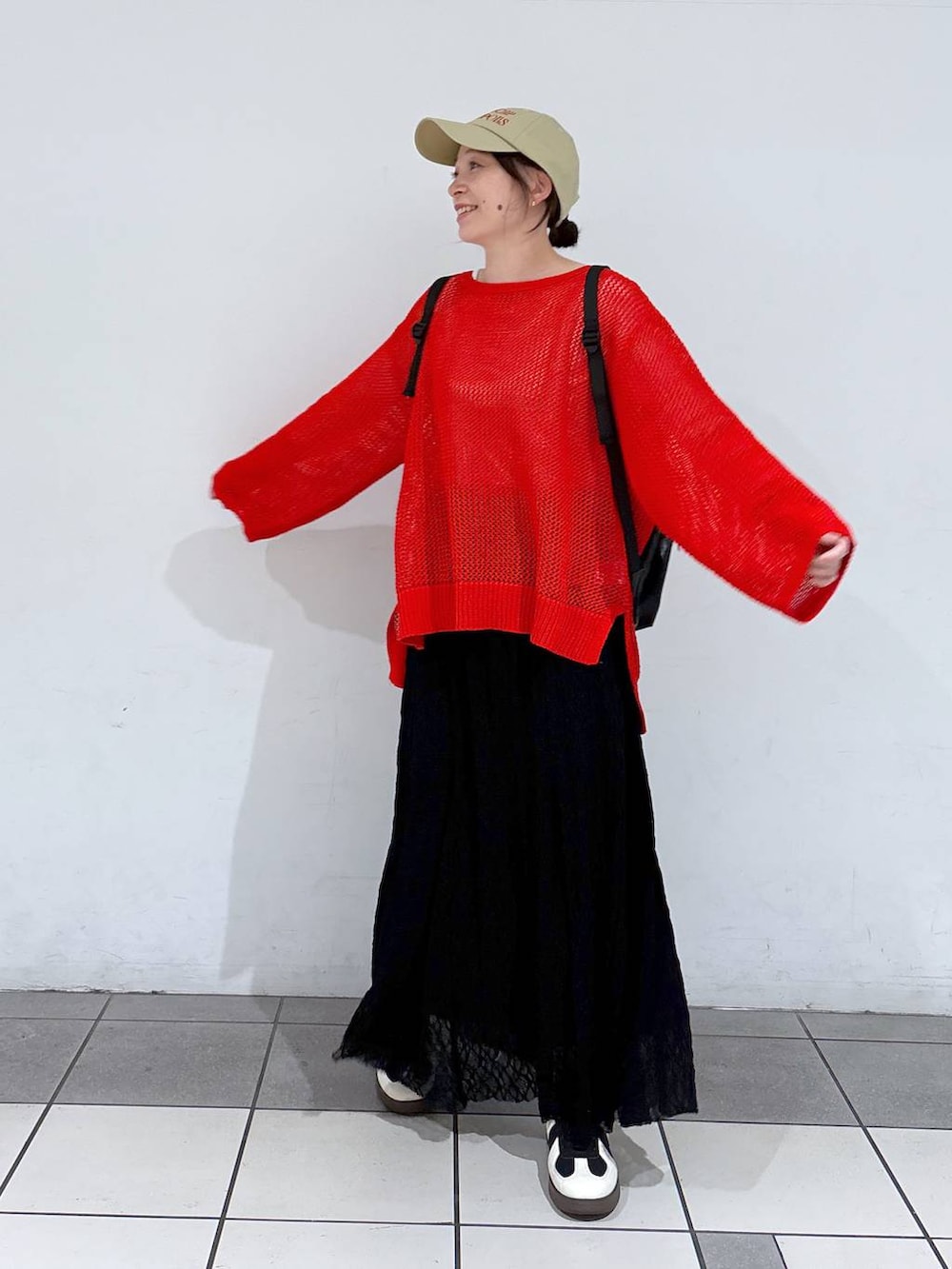 ブラック系のスニーカー、レッド系のニット/セーター、ブラック系のバックパック/リュックを着用したレディースの春コーディネートの2枚目の写真