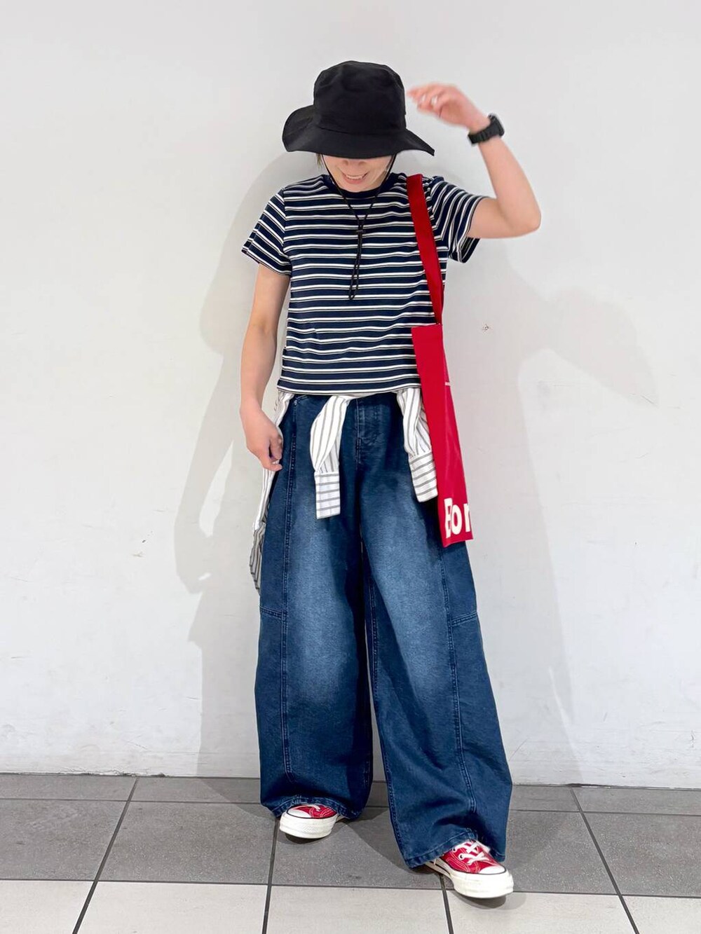 レッド系のトートバッグ、ブルー系のデニムパンツ、ホワイト系のシャツ/ブラウスを着用したレディースの春コーディネートの2枚目の写真