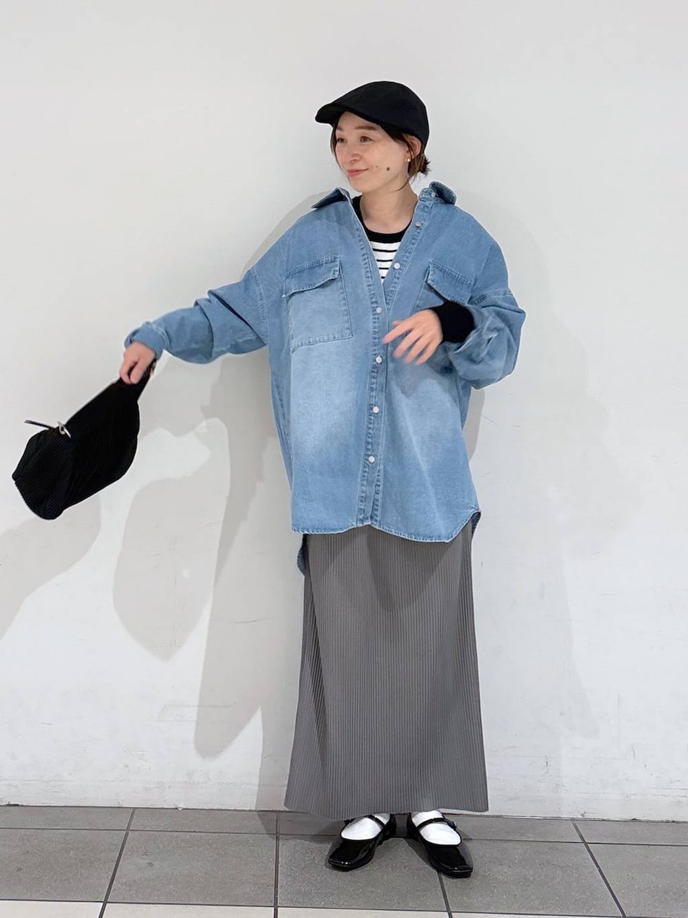 ホワイト系のニット/セーター、ブラック系のパンプス、ブルー系のシャツ/ブラウスを着用したレディースの春コーディネートの2枚目の写真