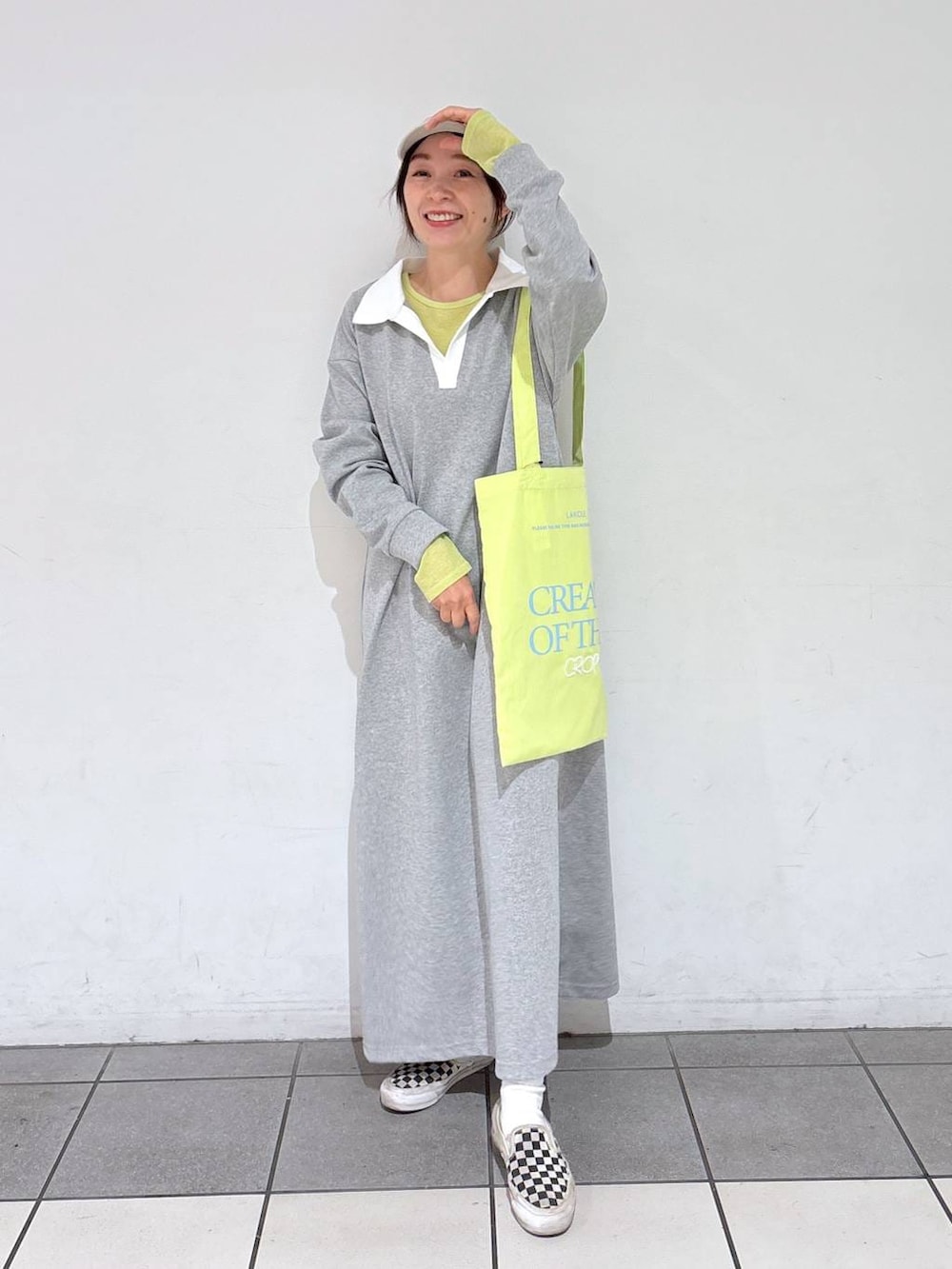 グリーン系のトートバッグ、グレー系のワンピース、ベージュ系のキャップを着用したレディースの冬コーディネートの2枚目の写真