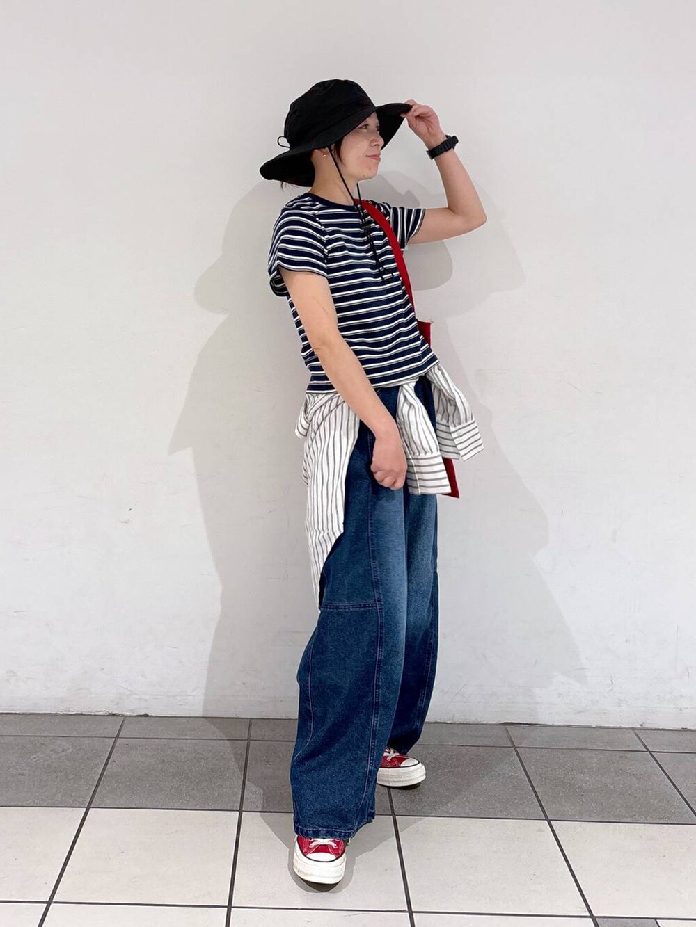 レッド系のトートバッグ、ブルー系のデニムパンツ、ホワイト系のシャツ/ブラウスを着用したレディースの春コーディネートの4枚目の写真