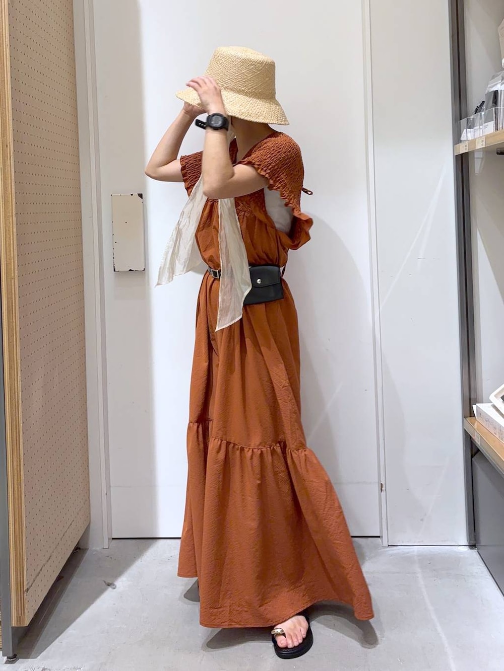 オレンジ系のワンピース、ブラック系のサンダル、ホワイト系のキャミソールを着用したレディースの夏コーディネートの2枚目の写真