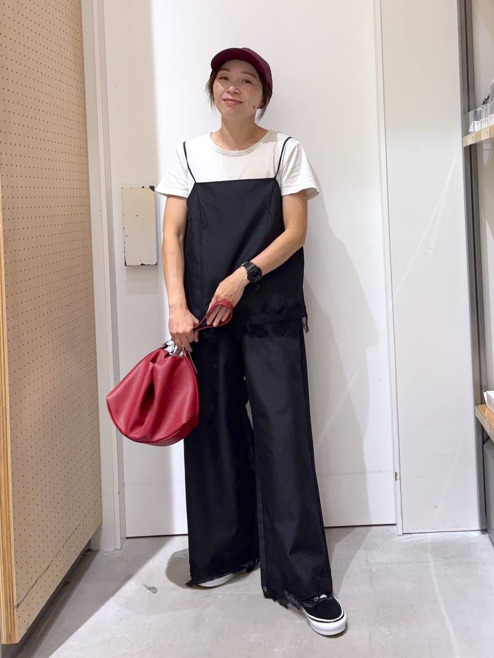 ブラック系のスラックス、ブラック系のキャミソール、レッド系のショルダーバッグを着用したレディースの夏コーディネートの6枚目の写真