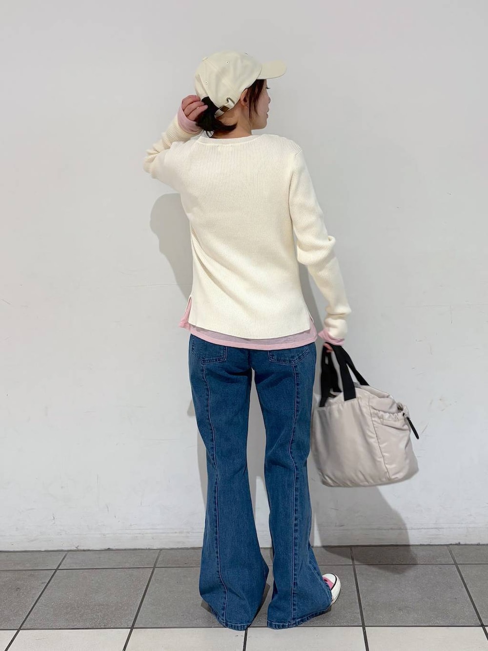 グレー系のトートバッグ、ホワイト系のニット/セーター、ブルー系のデニムパンツを着用したレディースの冬コーディネートの2枚目の写真