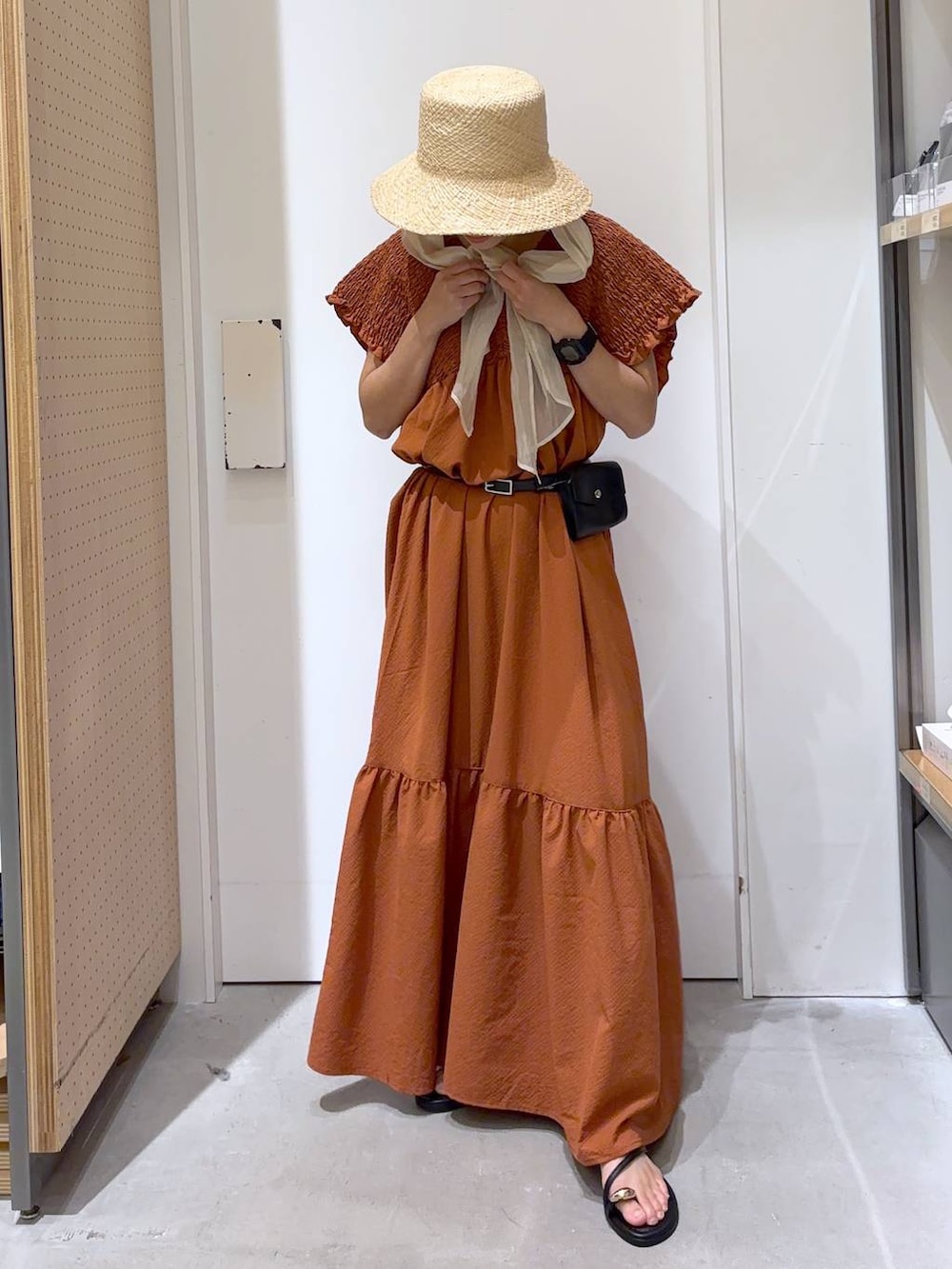 オレンジ系のワンピース、ブラック系のサンダル、ホワイト系のキャミソールを着用したレディースの夏コーディネートの5枚目の写真