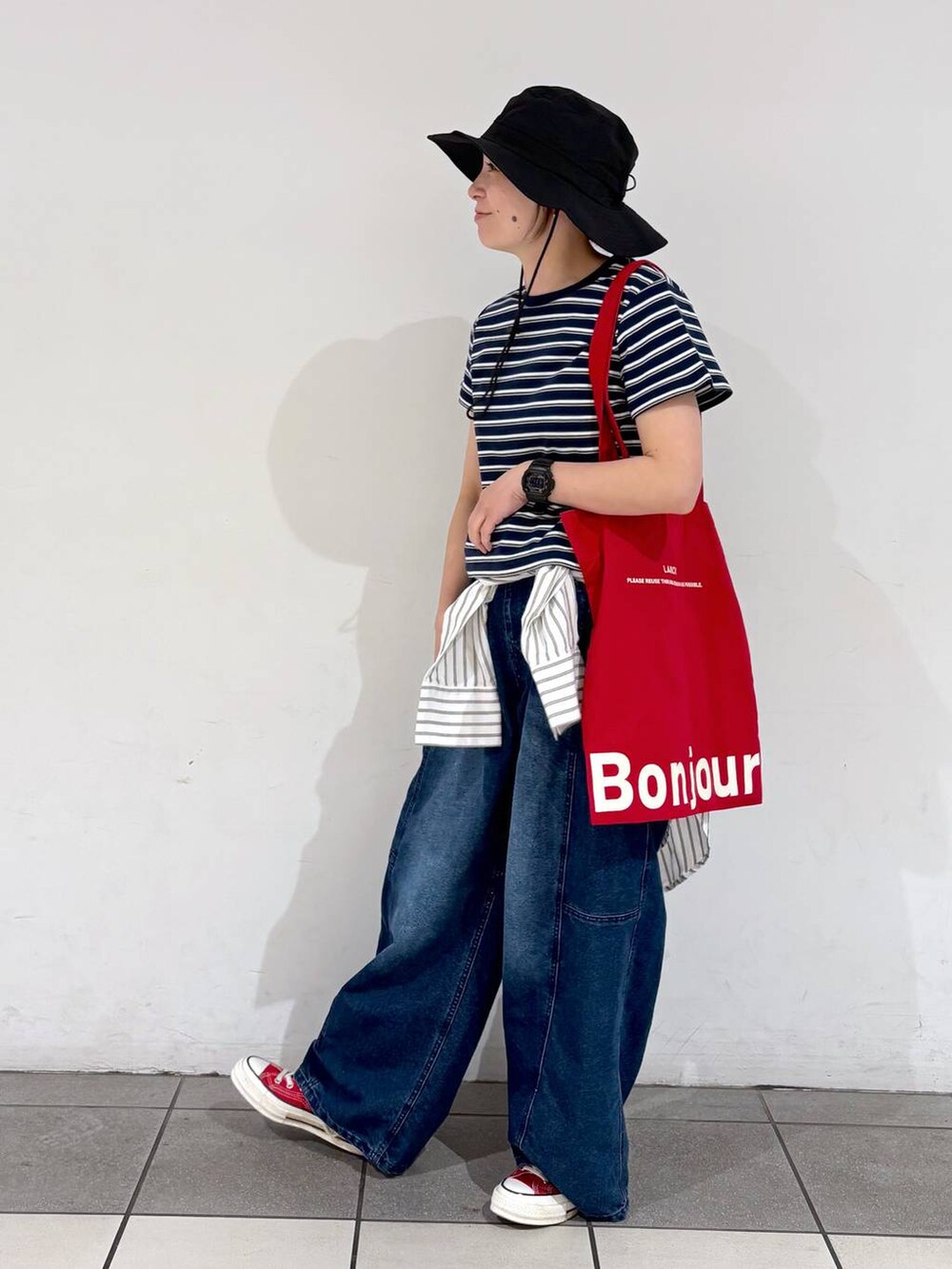レッド系のトートバッグ、ブルー系のデニムパンツ、ホワイト系のシャツ/ブラウスを着用したレディースの春コーディネートの3枚目の写真