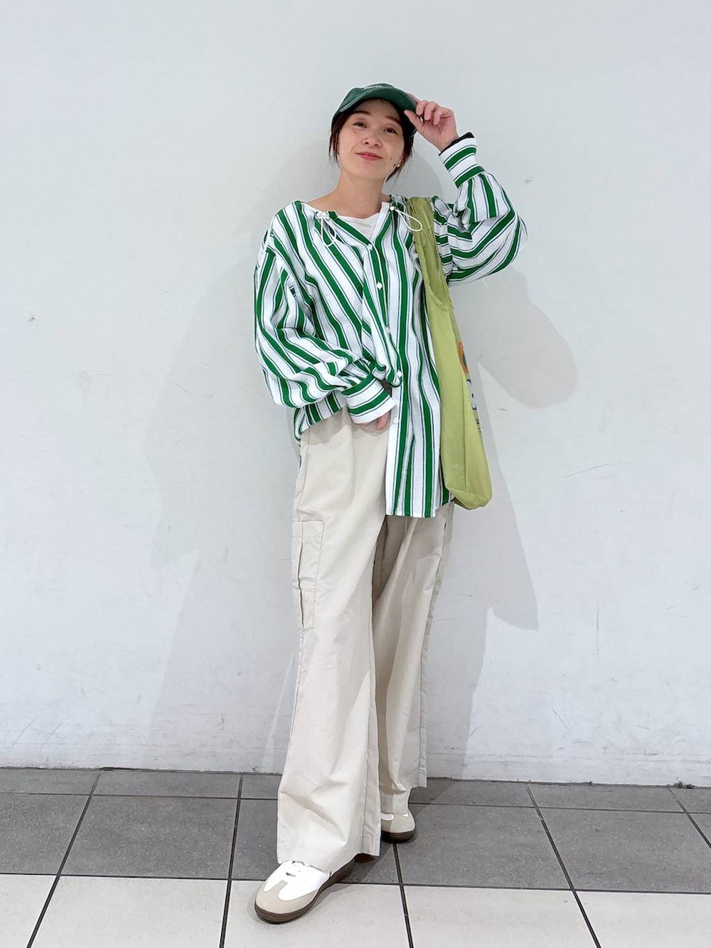 グリーン系のエコバッグ/サブバッグ、ホワイト系のスニーカー、グリーン系のシャツ/ブラウスを着用したレディースの春コーディネートの2枚目の写真