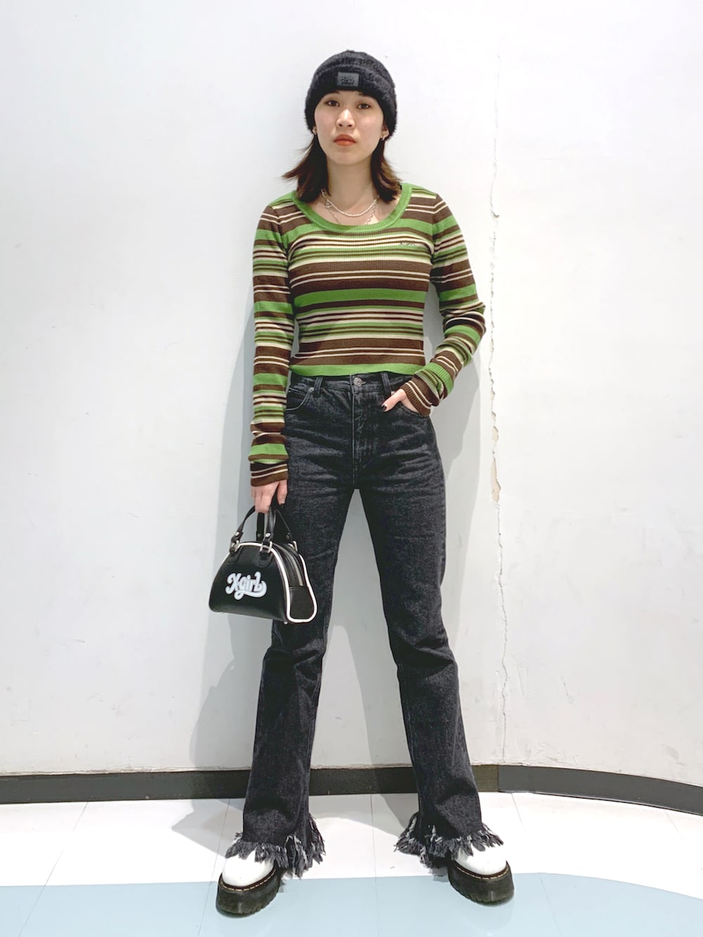 グレー系のパンツ、グリーン系のニット/セーター、ブラック系のニットキャップ/ビーニーを着用したレディースの秋コーディネートの2枚目の写真