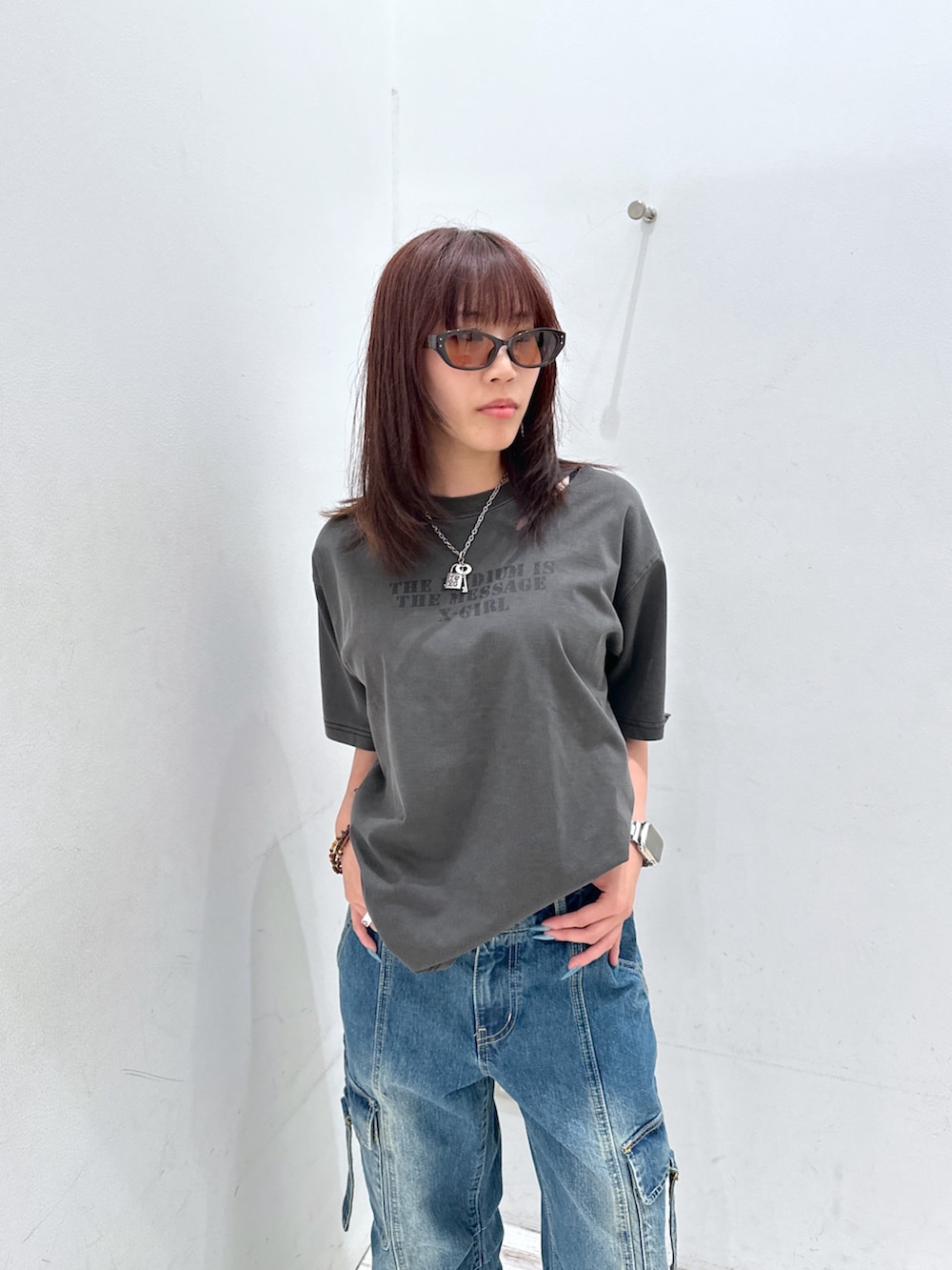 ブルー系のデニムパンツ、ブラック系のTシャツ/カットソー、ブラウン系のサングラスを着用したレディースの夏コーディネートの4枚目の写真