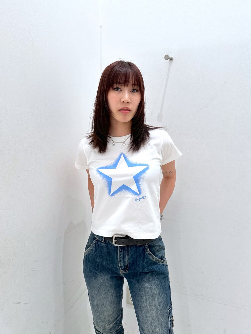 ブルー系のデニムパンツ、ホワイト系のTシャツ/カットソー、ホワイト系のハンドバッグを着用したレディースの夏コーディネートの4枚目の写真