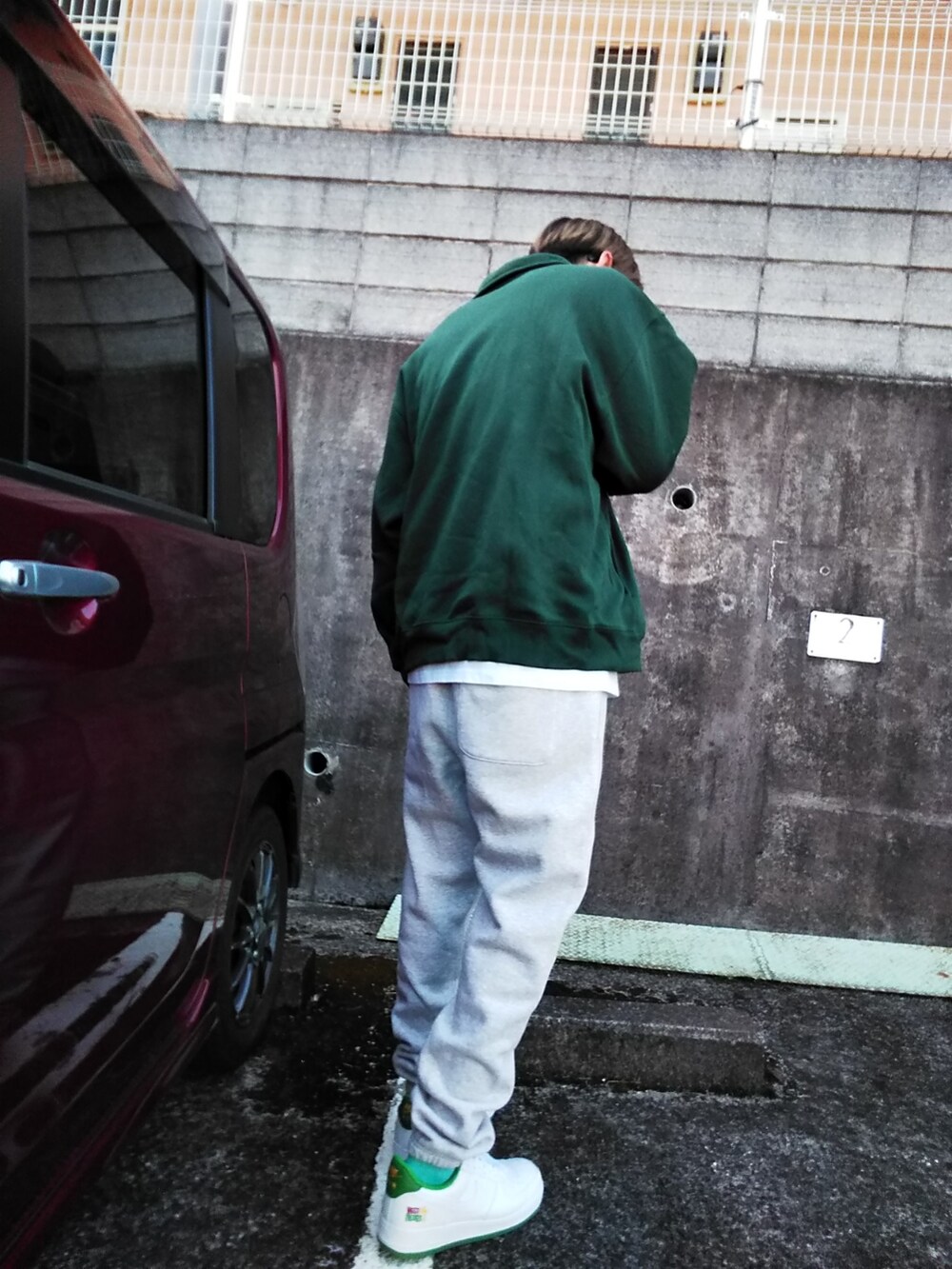 グレー系のスウェットパンツ、ホワイト系のスニーカー、グリーン系のスウェットを着用したメンズの冬コーディネートの2枚目の写真
