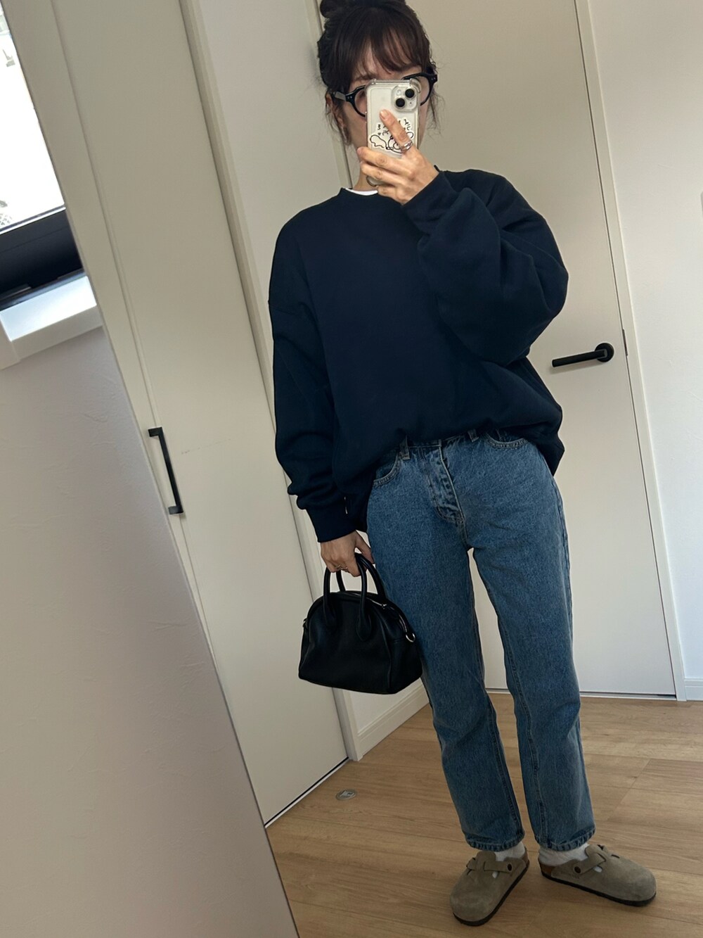 ブルー系のスウェット、ブルー系のデニムパンツ、ベージュ系のサンダルを着用したレディースの冬コーディネートの3枚目の写真