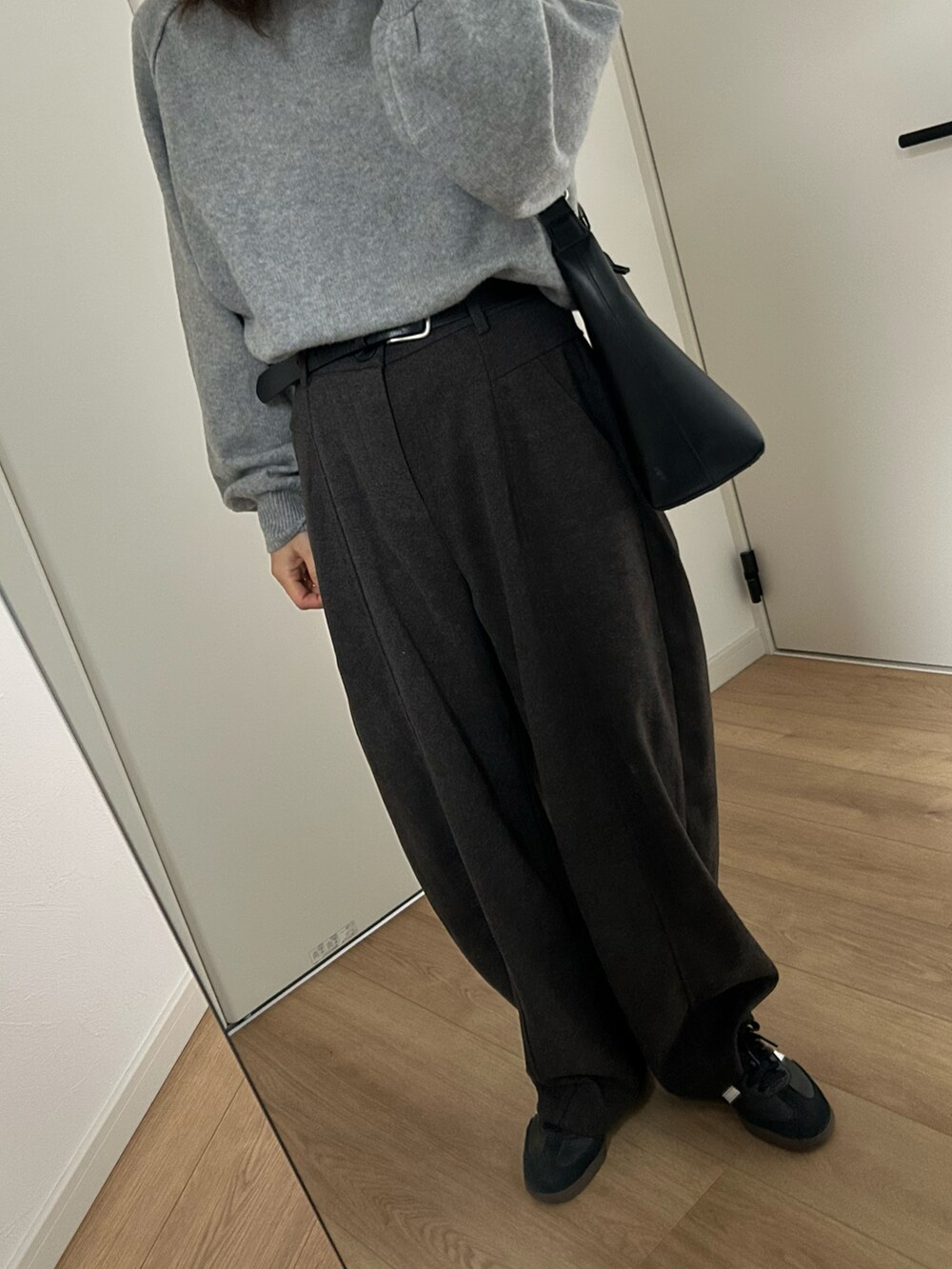 ブラック系のスニーカー、ブラック系のパンツ、グレー系のニット/セーターを着用したレディースの冬コーディネートの2枚目の写真