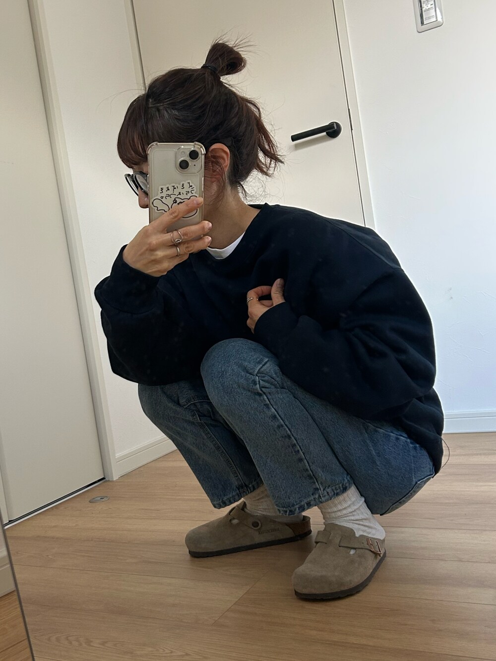 ブルー系のスウェット、ブルー系のデニムパンツ、ベージュ系のサンダルを着用したレディースの冬コーディネートの2枚目の写真