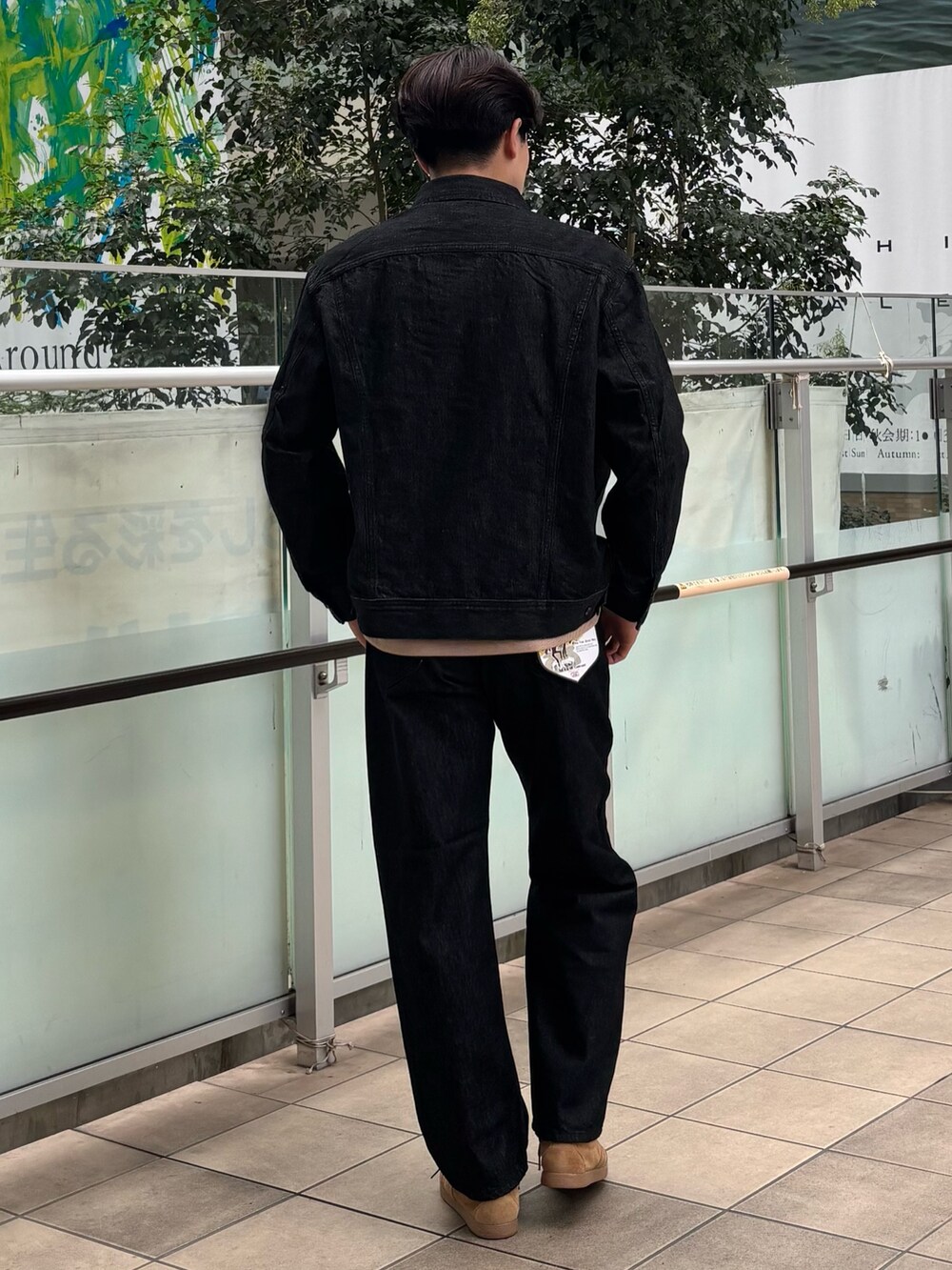 ブラック系のデニムジャケット、ベージュ系のTシャツ/カットソー、ブラック系のデニムパンツを着用したメンズの秋コーディネートの3枚目の写真