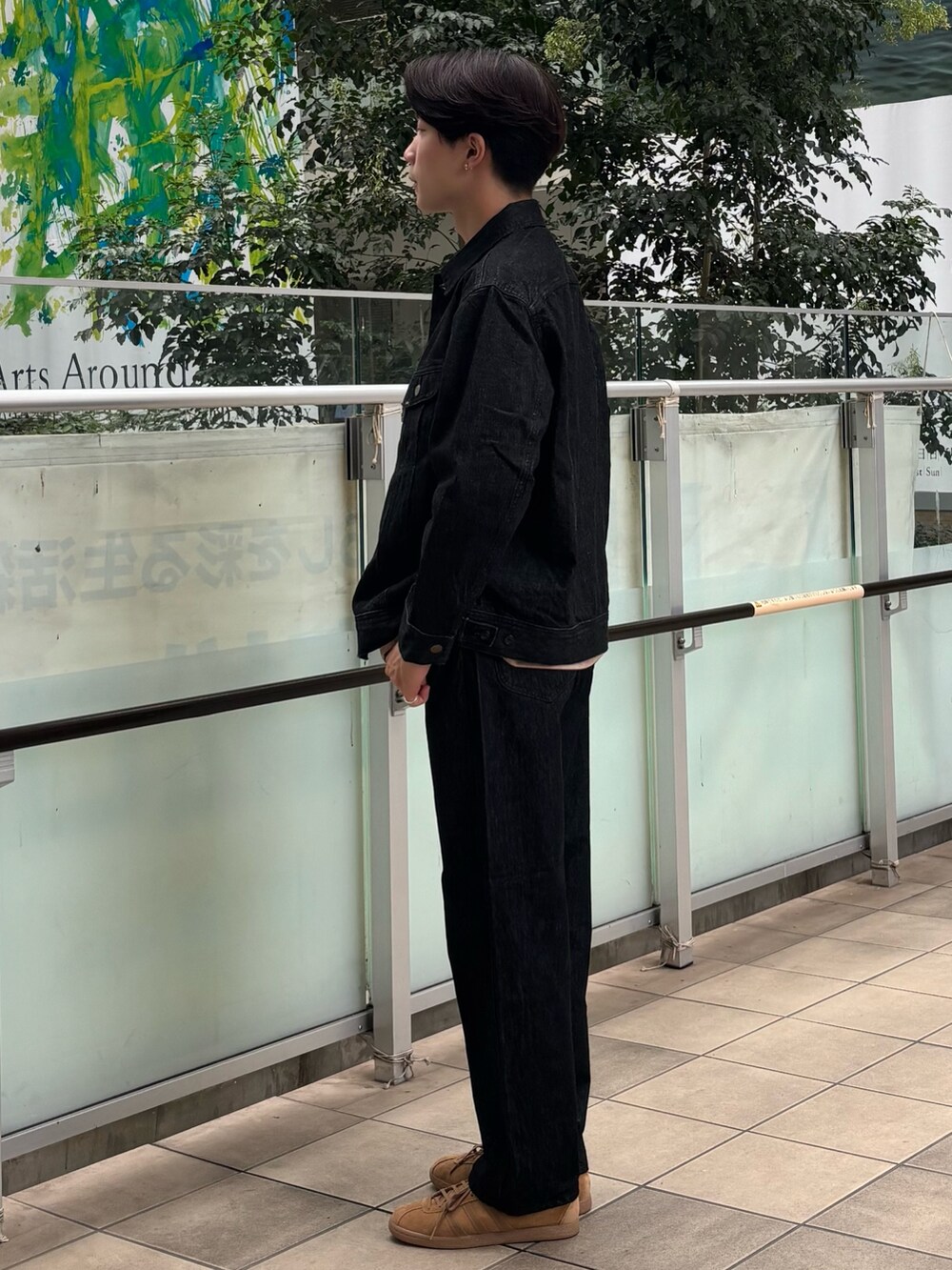 ブラック系のデニムジャケット、ベージュ系のTシャツ/カットソー、ブラック系のデニムパンツを着用したメンズの秋コーディネートの2枚目の写真
