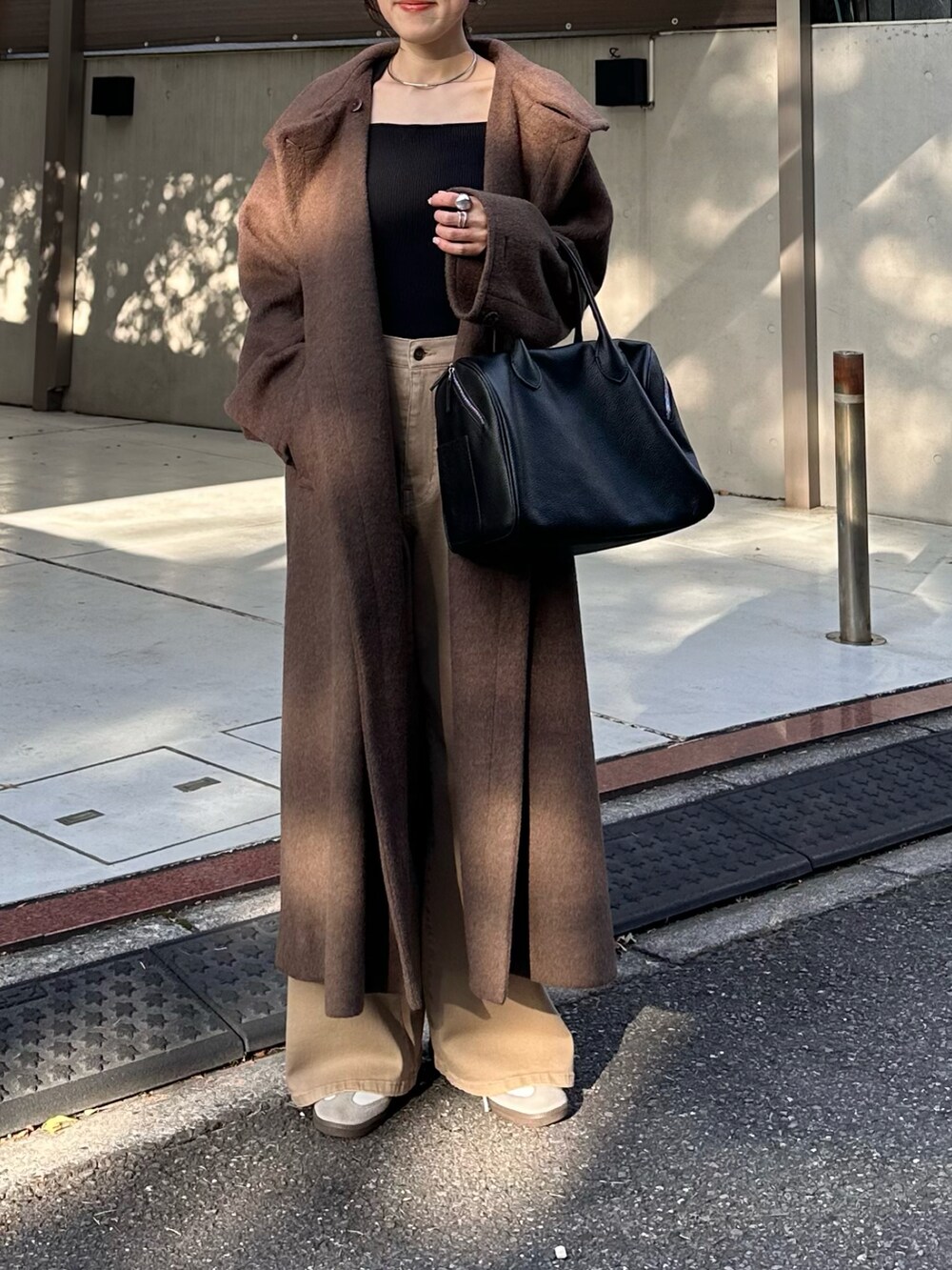 ブラック系のボストンバッグ、グレー系のその他アウター、ブルー系のデニムパンツを着用したレディースの秋コーディネートの2枚目の写真