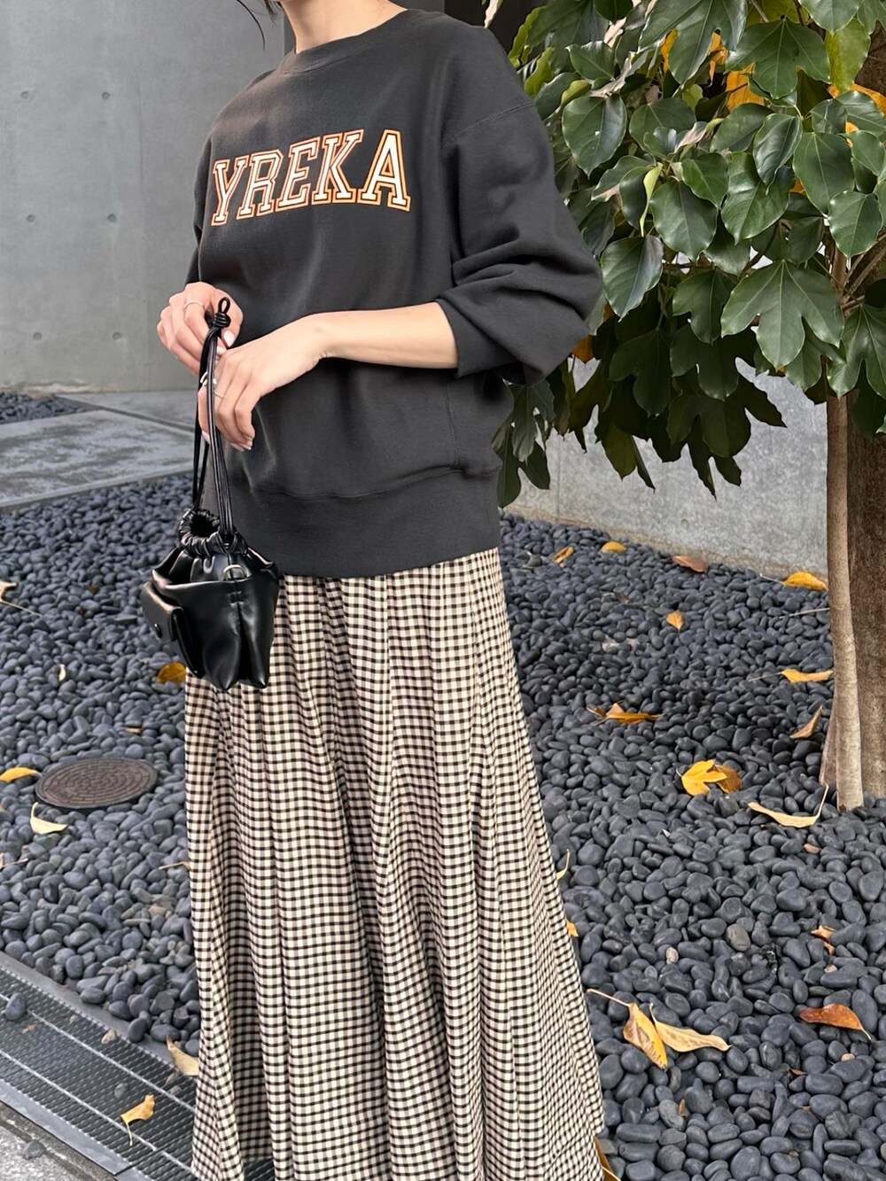 グレー系のスウェット、ベージュ系のスカート、ブラック系のショルダーバッグを着用したレディースの秋コーディネートの3枚目の写真