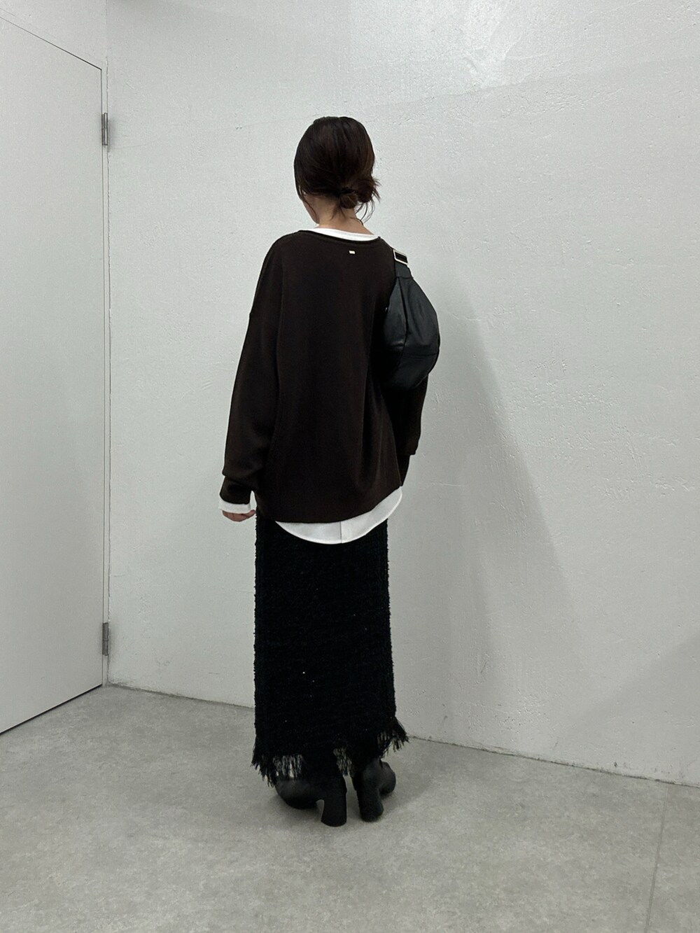 ブラウン系のニット/セーター、ブラック系のスカート、ホワイト系のシャツ/ブラウスを着用したレディースの秋コーディネートの3枚目の写真