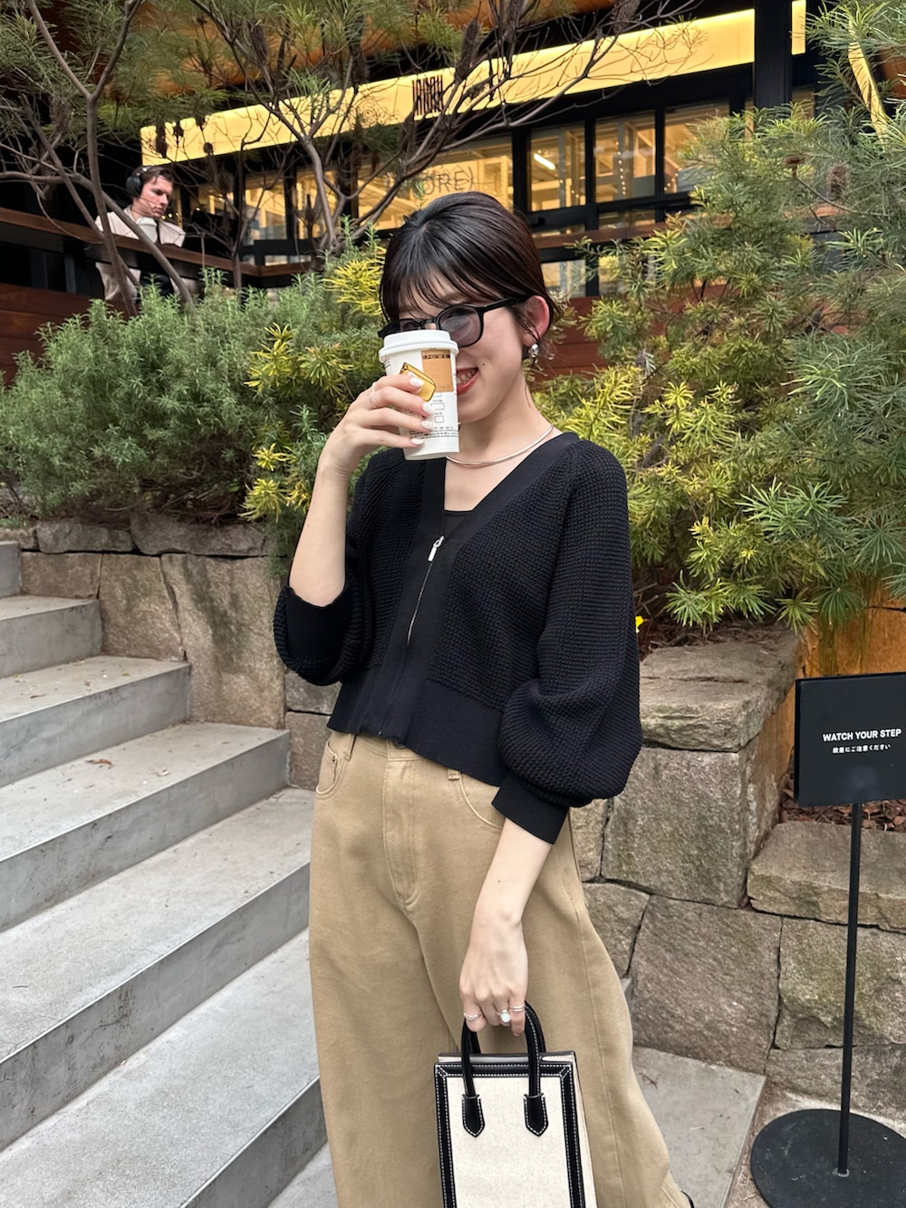 ブラック系のショルダーバッグ、ブラック系のカーディガン/ボレロ、ベージュ系のデニムパンツを着用したレディースの春コーディネートの4枚目の写真