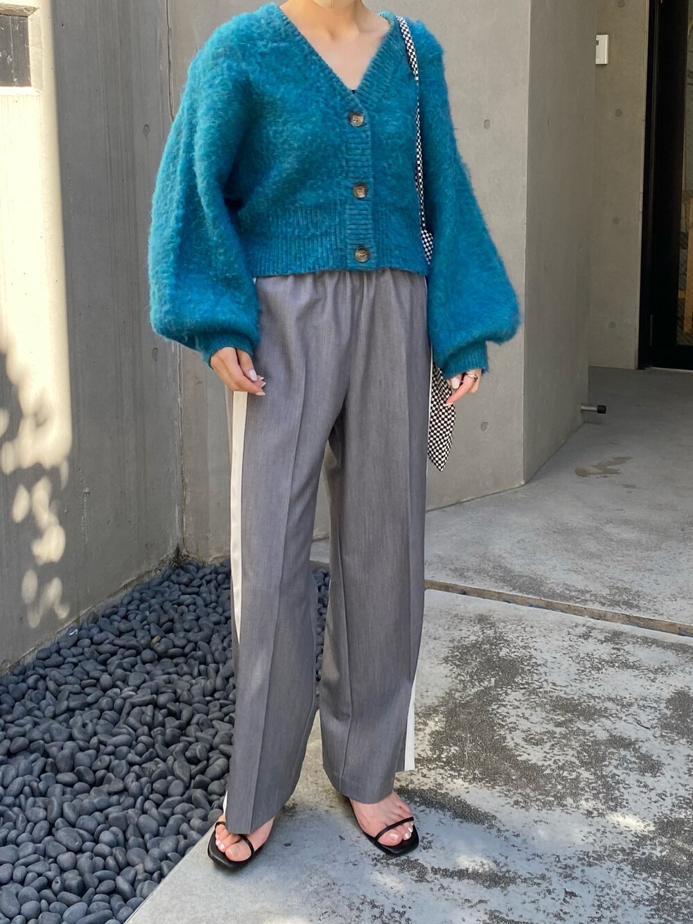 ブルー系のカーディガン/ボレロ、グレー系のスラックスを着用したレディースの秋コーディネートの3枚目の写真