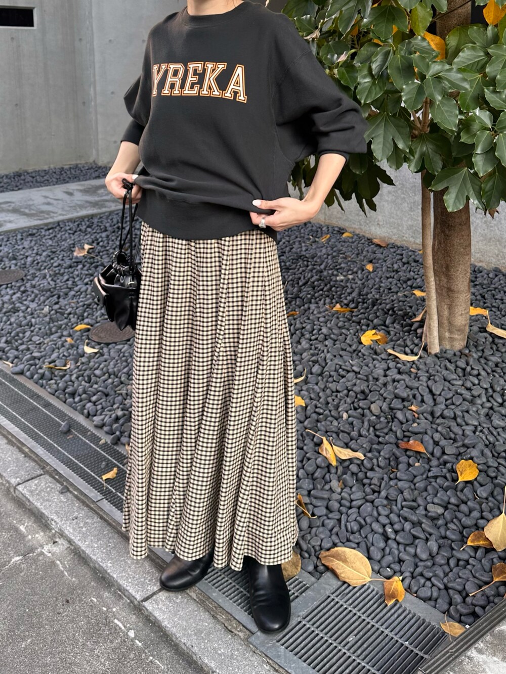 グレー系のスウェット、ベージュ系のスカート、ブラック系のショルダーバッグを着用したレディースの秋コーディネートの2枚目の写真