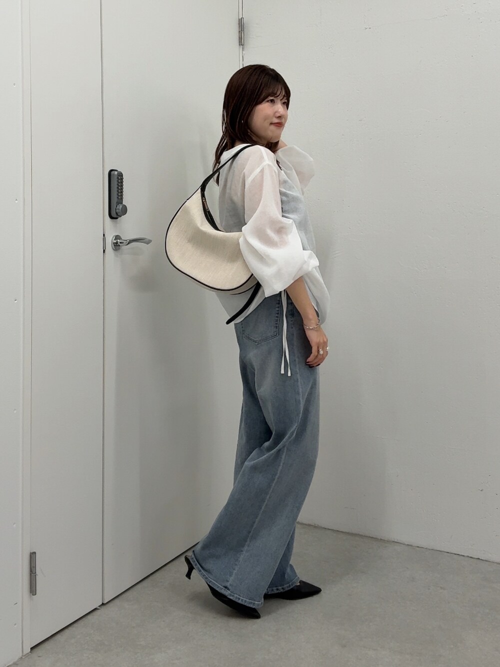 ホワイト系のシャツ/ブラウス、ブルー系のデニムパンツ、ブラック系のショルダーバッグを着用したレディースの春コーディネートの2枚目の写真