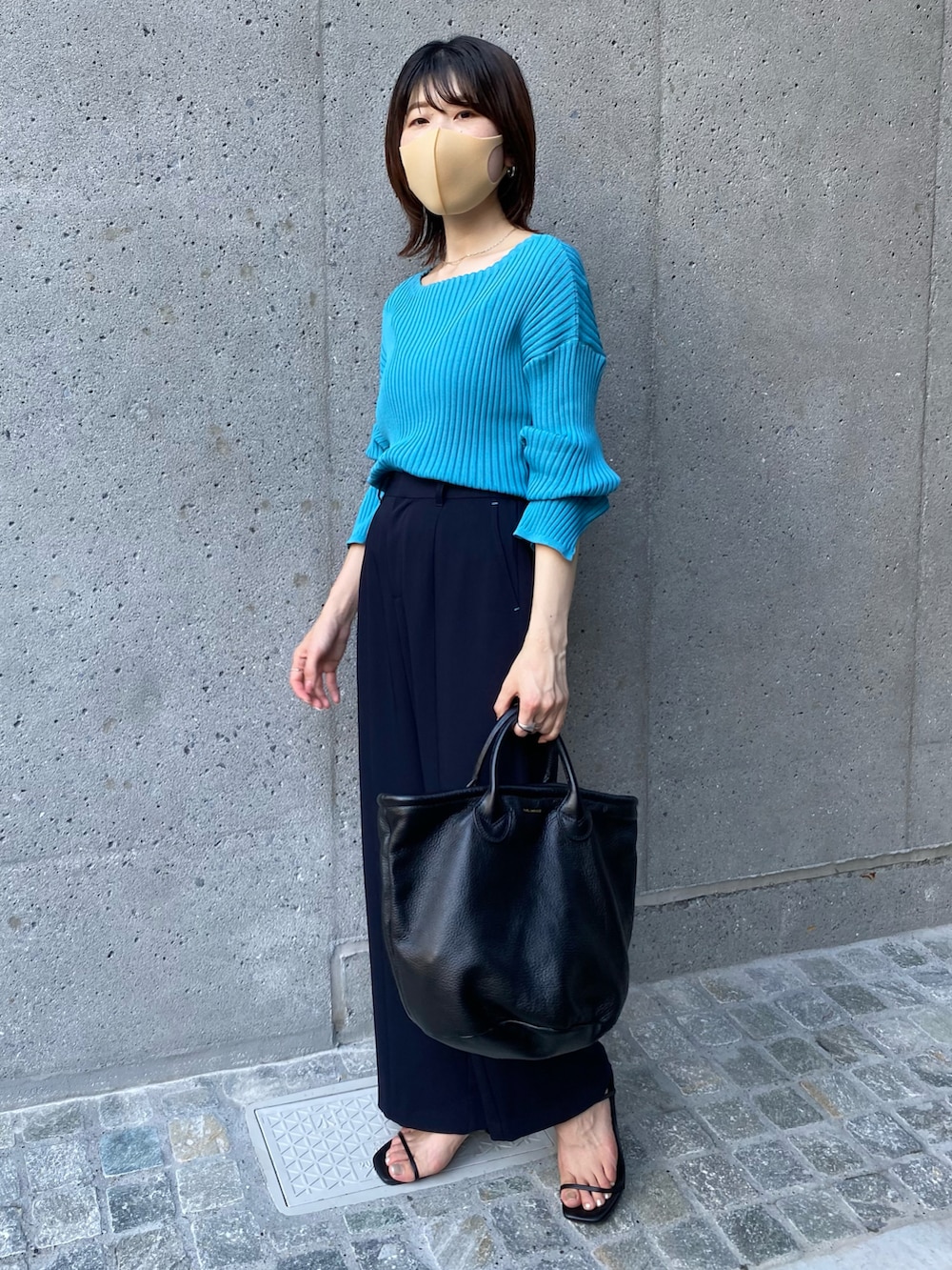 ブラック系のトートバッグ、ブルー系のニット/セーター、ブルー系のスラックスを着用したレディースの夏コーディネートの3枚目の写真