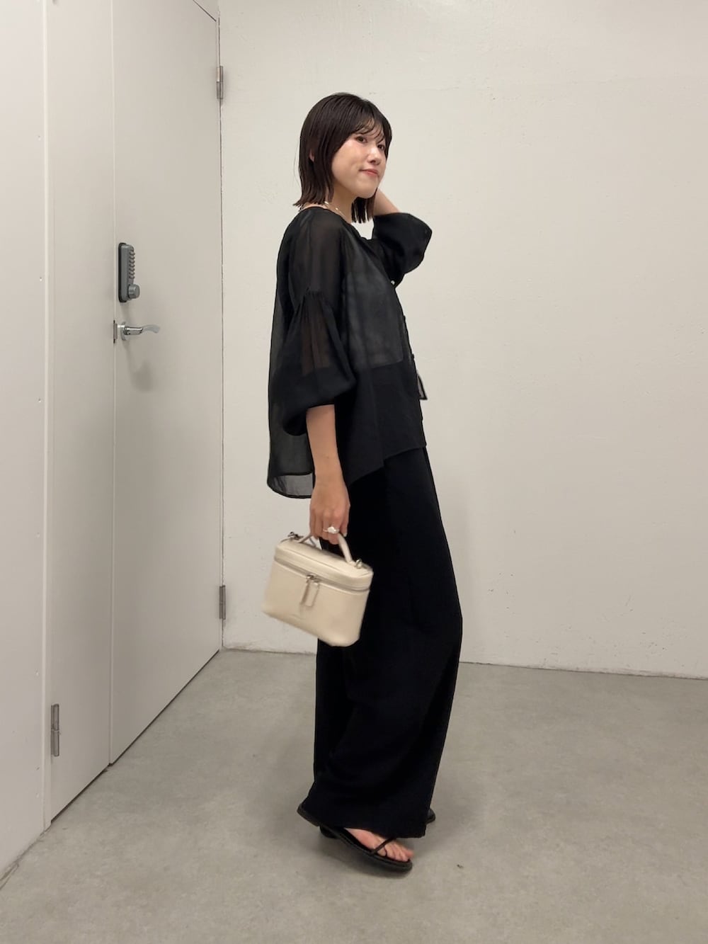 ブラック系のシャツ/ブラウス、ブラック系のスラックス、ホワイト系のショルダーバッグを着用したレディースの春コーディネートの3枚目の写真