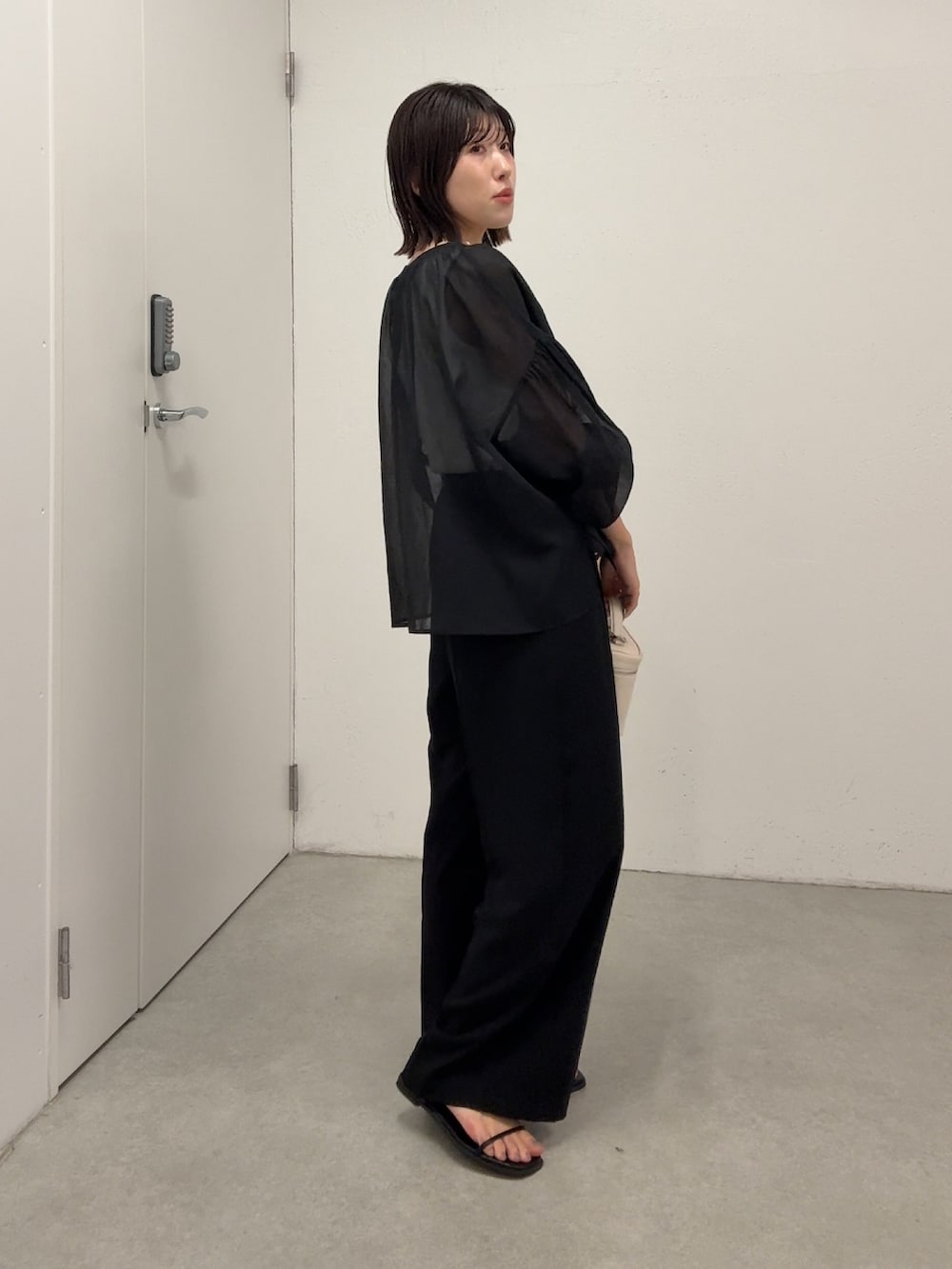 ブラック系のシャツ/ブラウス、ブラック系のスラックス、ホワイト系のショルダーバッグを着用したレディースの春コーディネートの2枚目の写真