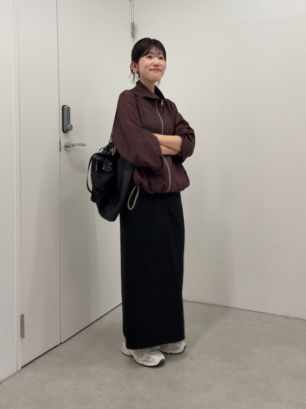 ブラウン系のマウンテンパーカー、ブラック系のスカート、ブラック系のトートバッグを着用したレディースの春コーディネートの2枚目の写真