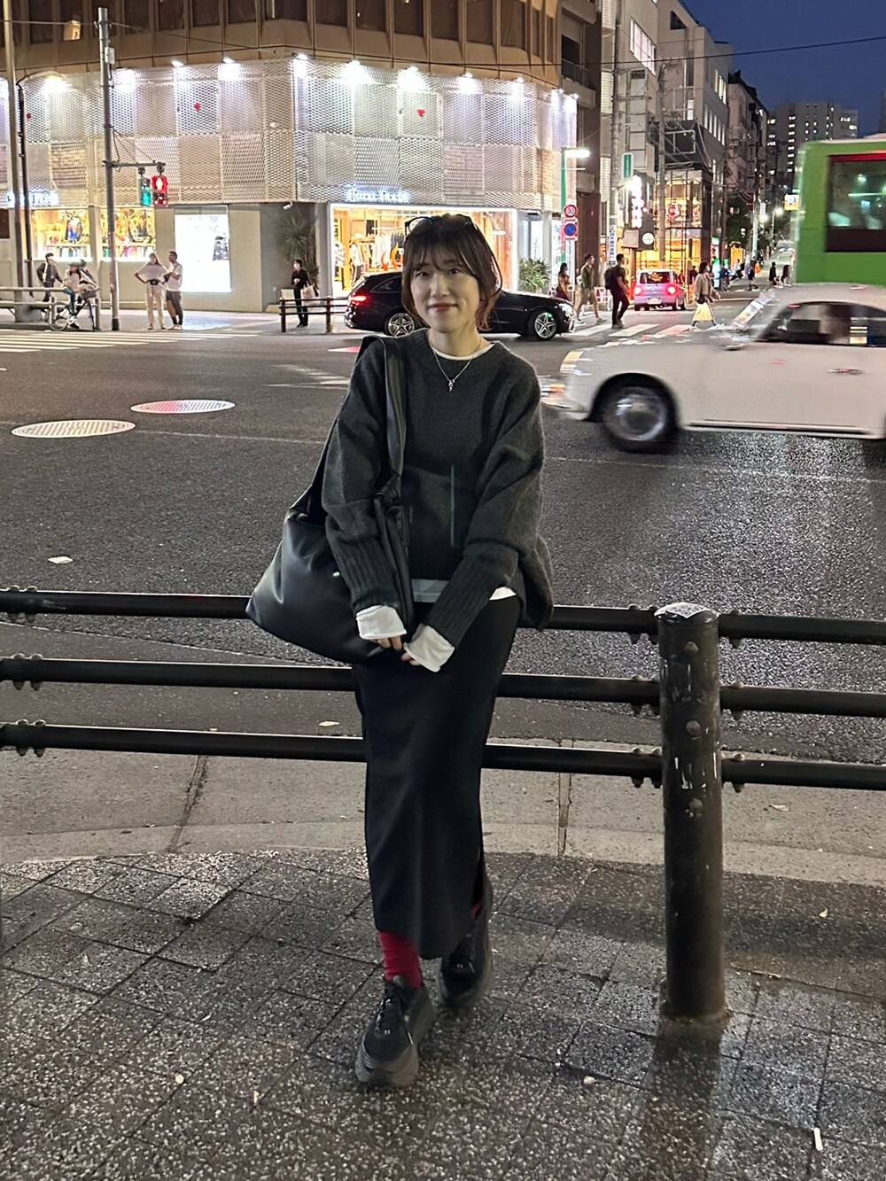 グレー系のニット/セーター、ブラック系のスカート、ホワイト系のTシャツ/カットソーを着用したレディースの秋コーディネートの2枚目の写真