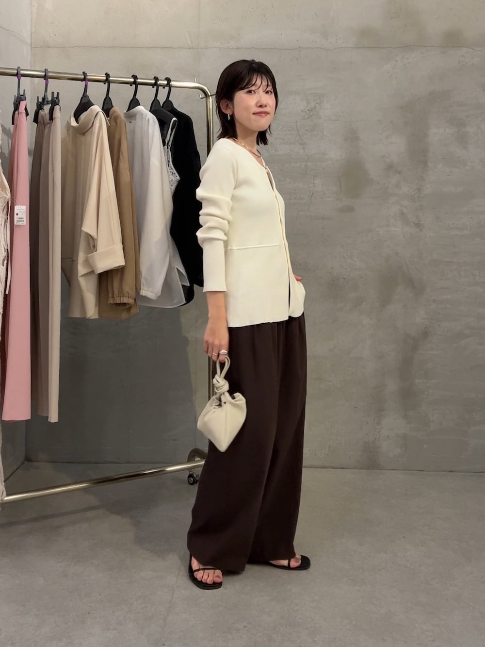 ホワイト系のカーディガン/ボレロ、ブラウン系のスラックス、ホワイト系のショルダーバッグを着用したレディースの春コーディネートの3枚目の写真
