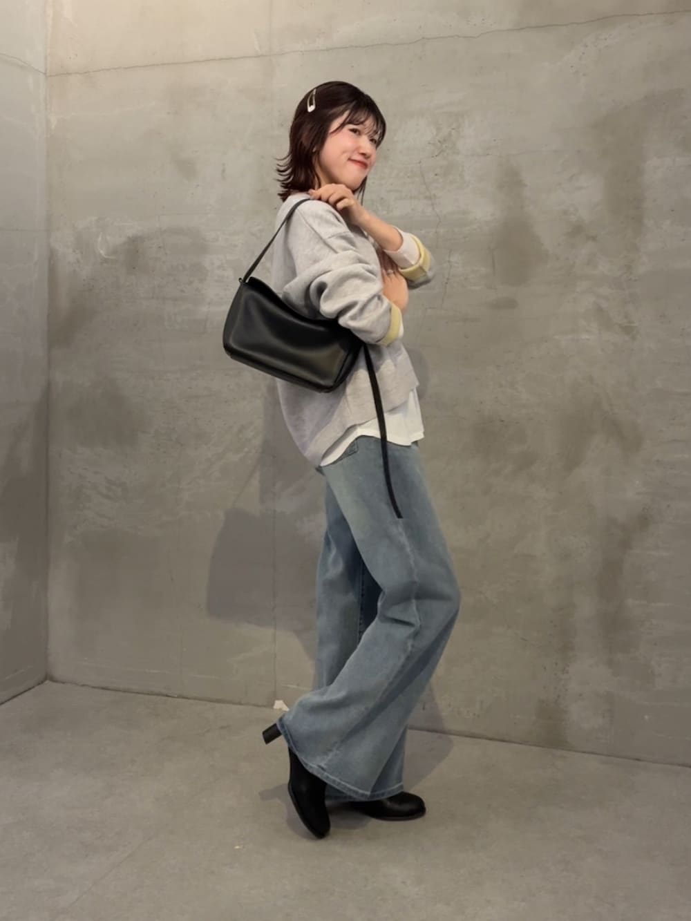 グレー系のニット/セーター、ホワイト系のTシャツ/カットソー、ブルー系のデニムパンツを着用したレディースの冬コーディネートの3枚目の写真