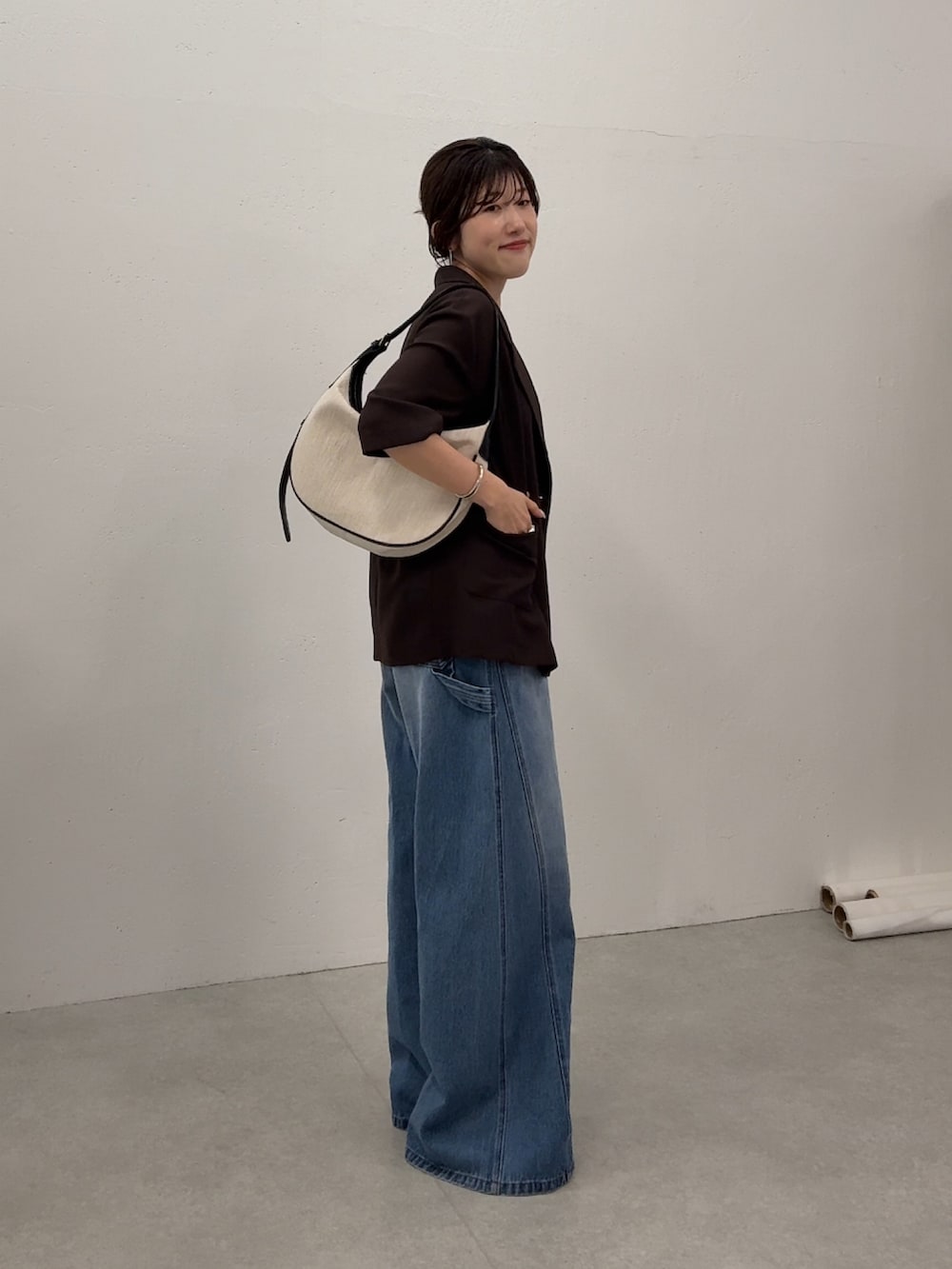 ブラウン系のテーラードジャケット、ブルー系のデニムパンツ、ゴールド系のネックレスを着用したレディースの夏コーディネートの2枚目の写真