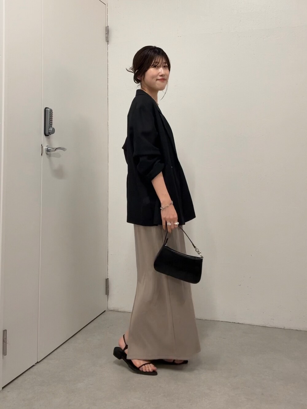 ベージュ系のワンピース、ブラック系のテーラードジャケット、ホワイト系のショルダーバッグを着用したレディースの夏コーディネートの2枚目の写真