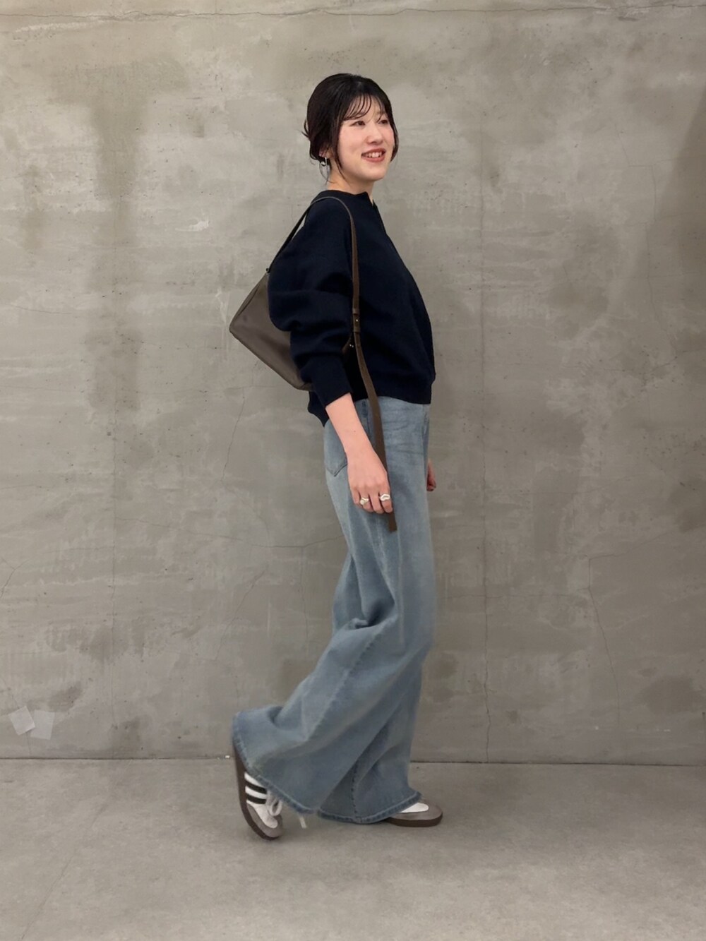 グレー系のニット/セーター、ブルー系のデニムパンツを着用したレディースの冬コーディネートの2枚目の写真