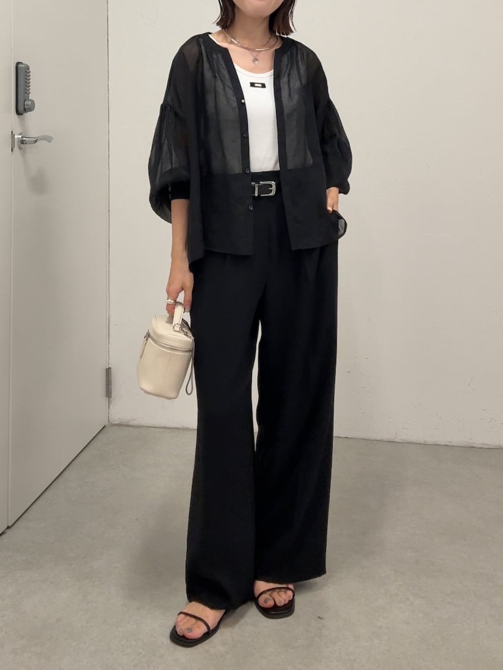 ブラック系のシャツ/ブラウス、ブラック系のスラックス、ホワイト系のショルダーバッグを着用したレディースの春コーディネートの5枚目の写真