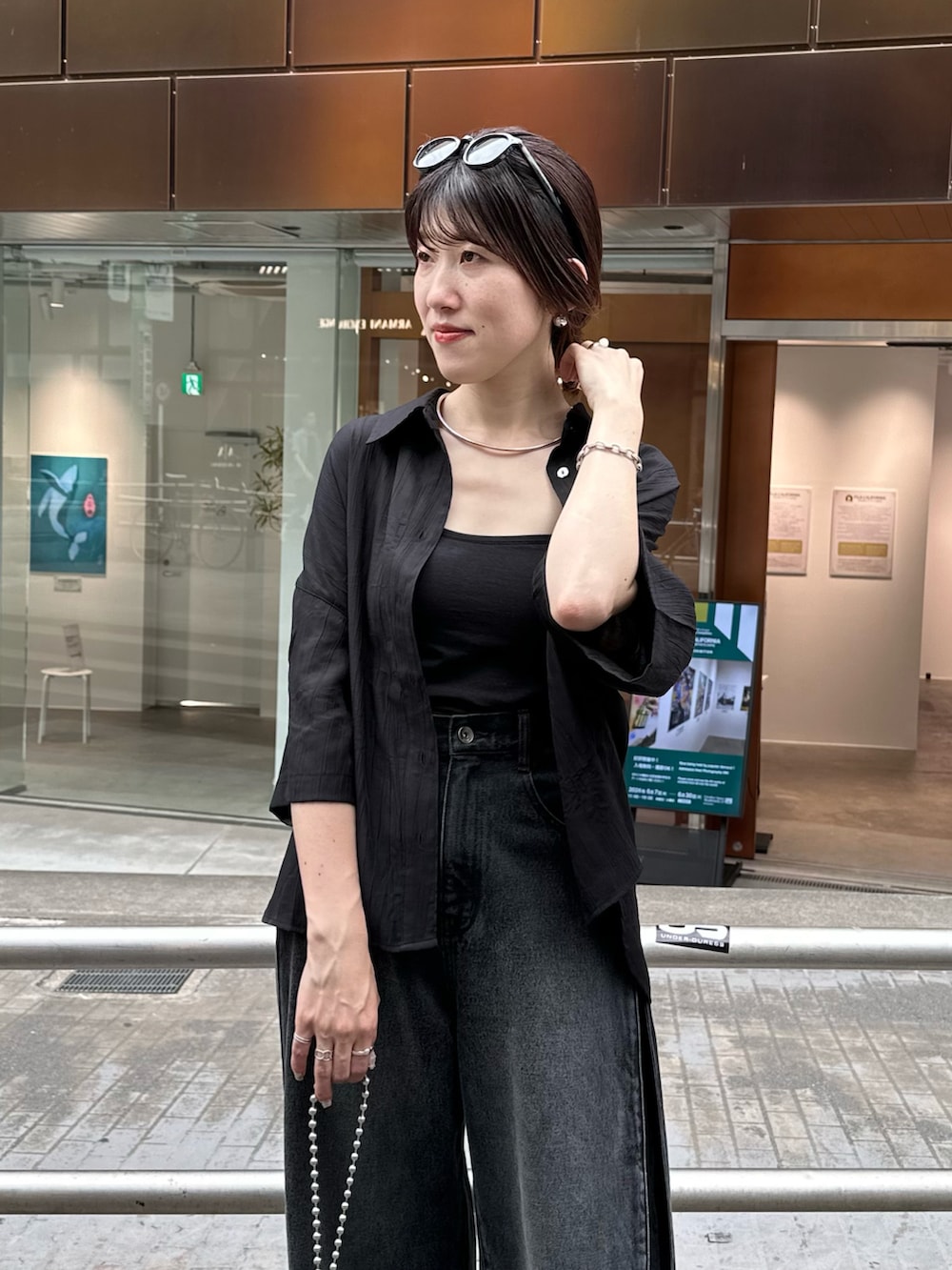 ブラック系のデニムパンツ、ブラック系のシャツ/ブラウス、ブラック系のショルダーバッグを着用したレディースの夏コーディネートの4枚目の写真