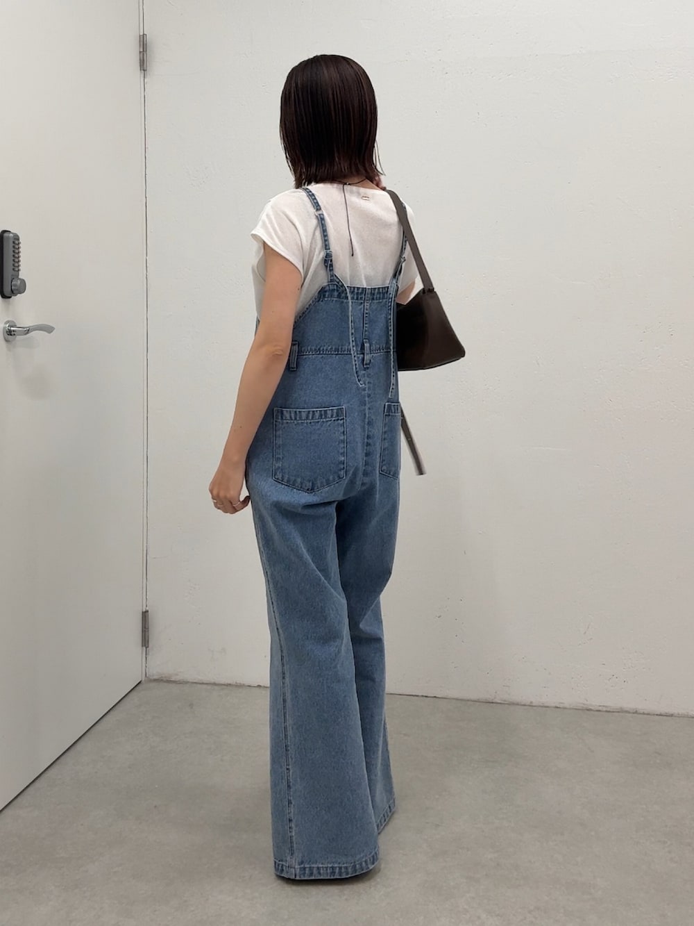 ブルー系のサロペット/オーバーオール、ホワイト系のTシャツ/カットソー、ブラウン系のショルダーバッグを着用したレディースの春コーディネートの3枚目の写真