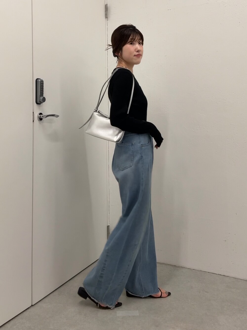 ブラック系のニット/セーター、ブルー系のデニムパンツ、シルバー系のショルダーバッグを着用したレディースの夏コーディネートの3枚目の写真