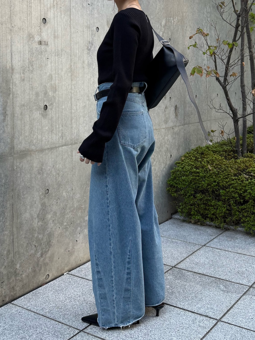 ブルー系のデニムパンツ、ブラック系のニット/セーター、ブラック系のパンプスを着用したレディースの秋コーディネートの3枚目の写真