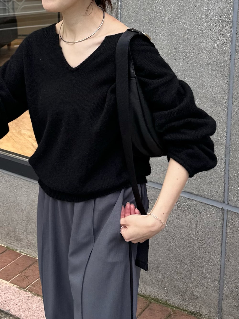 ブラック系のニット/セーター、ブルー系のスラックスを着用したレディースの秋コーディネートの2枚目の写真