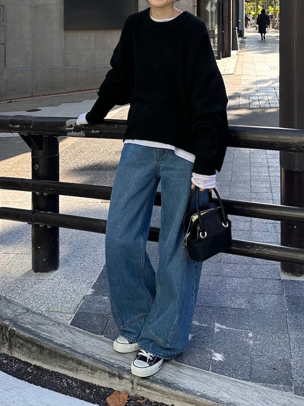 ブラック系のニット/セーター、ブラック系のバッグ、ブラック系のデニムパンツを着用したレディースの秋コーディネートの3枚目の写真