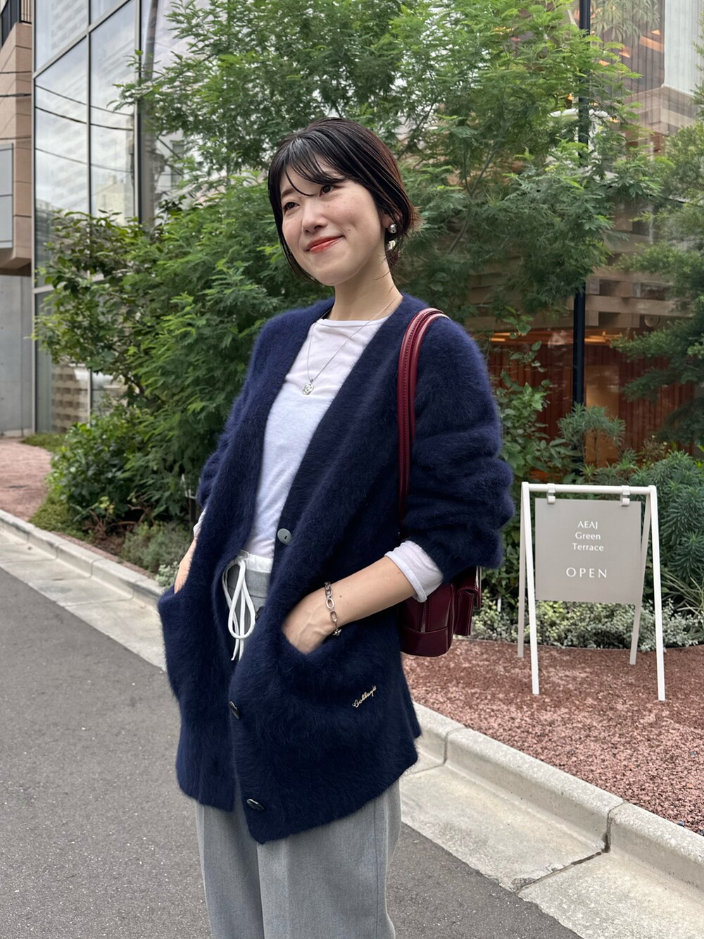 ブルー系のカーディガン/ボレロ、ホワイト系のTシャツ/カットソー、ブラック系のバッグを着用したレディースの秋コーディネートの4枚目の写真