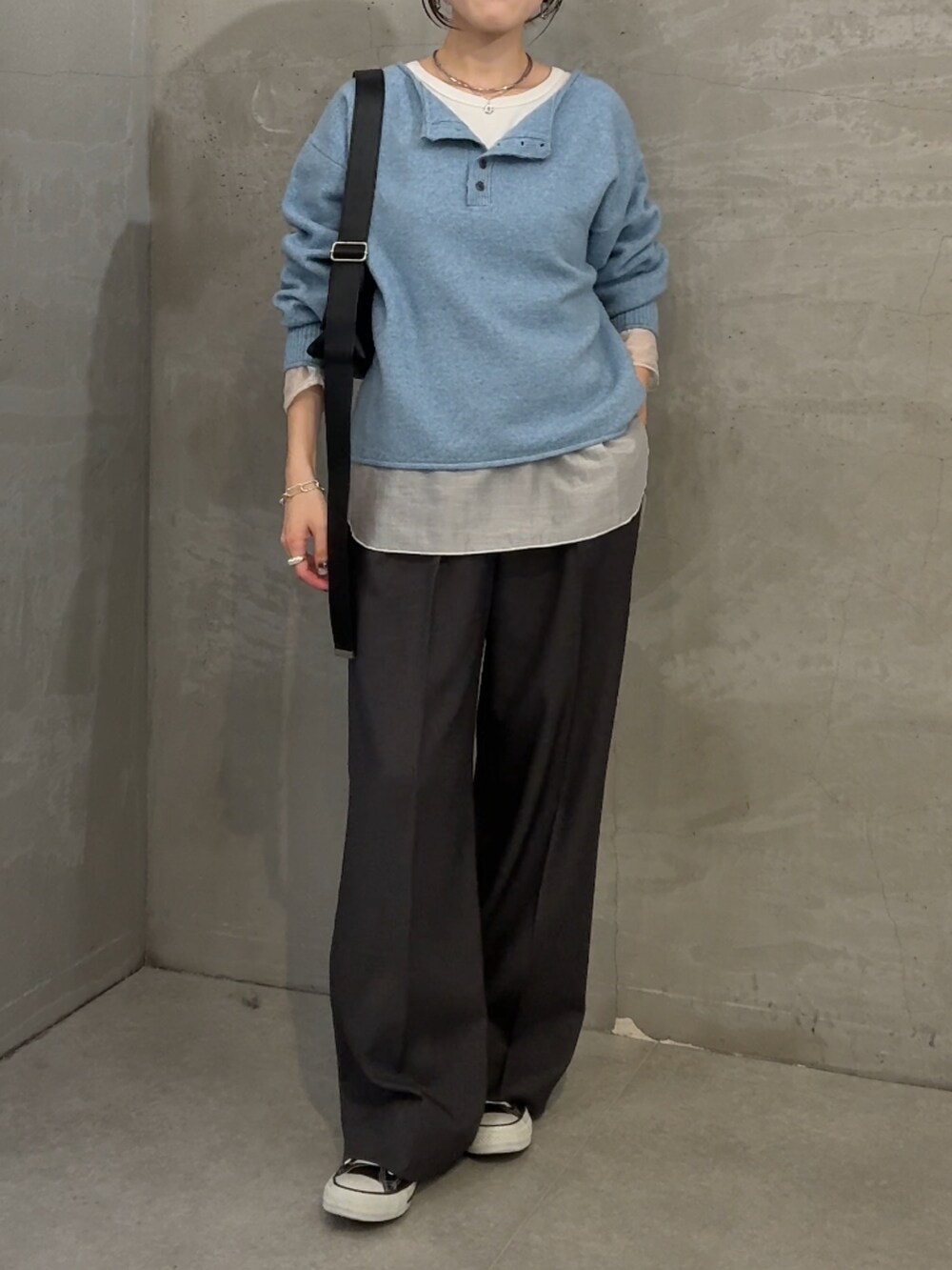 ブルー系のニット/セーター、ホワイト系のTシャツ/カットソー、グレー系のスラックスを着用したレディースの秋コーディネートの4枚目の写真