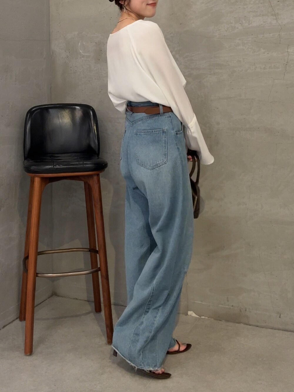 ブルー系のデニムパンツ、ホワイト系のシャツ/ブラウス、ブラウン系のショルダーバッグを着用したレディースの夏コーディネートの2枚目の写真