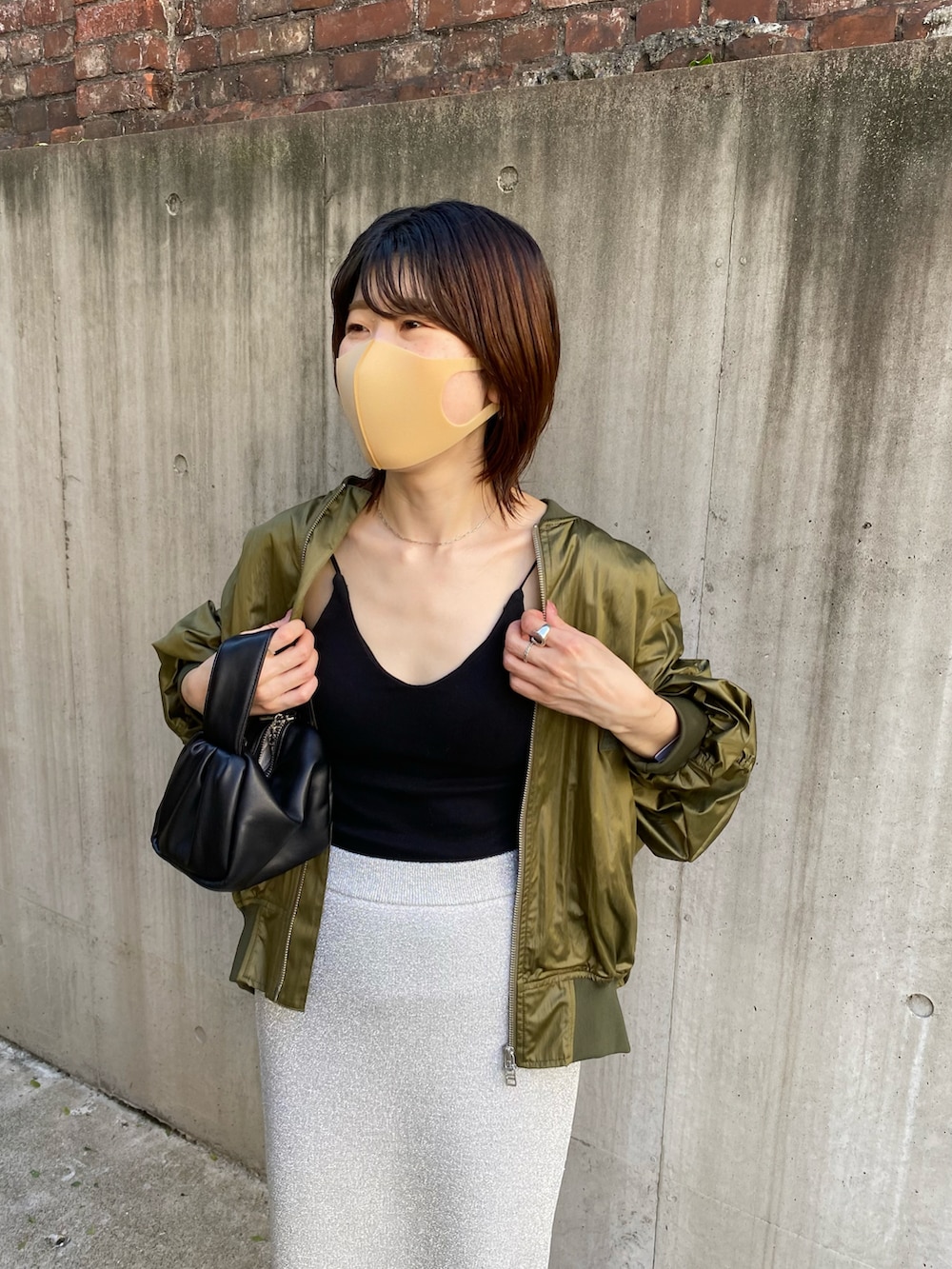 グリーン系のMA-1、ブラック系のキャミソール、ブラック系のショルダーバッグを着用したレディースの夏コーディネートの2枚目の写真