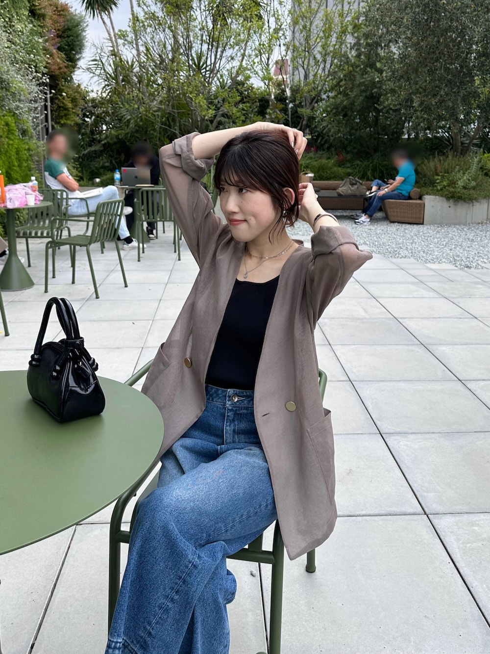 ブラック系のバッグ、ブラウン系のノーカラージャケット、ブルー系のデニムパンツを着用したレディースの夏コーディネートの4枚目の写真