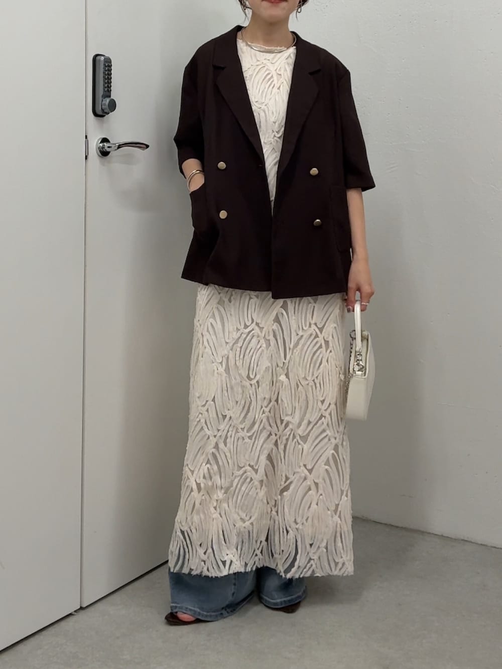 ホワイト系のワンピース、ブラウン系のテーラードジャケット、ホワイト系のショルダーバッグを着用したレディースの春コーディネートの5枚目の写真